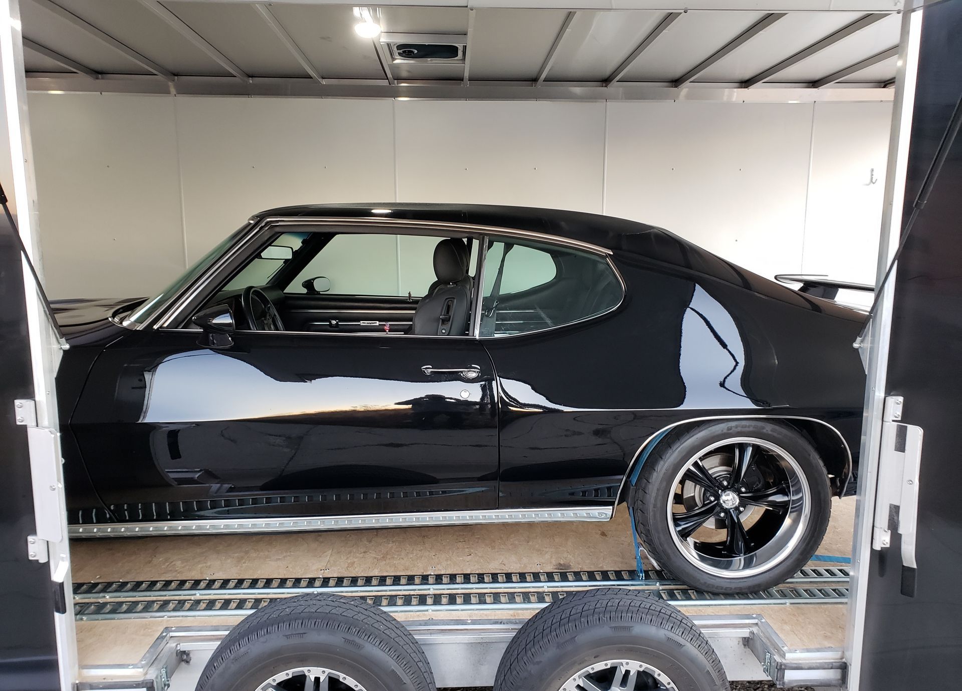 A black car is sitting inside of a trailer.