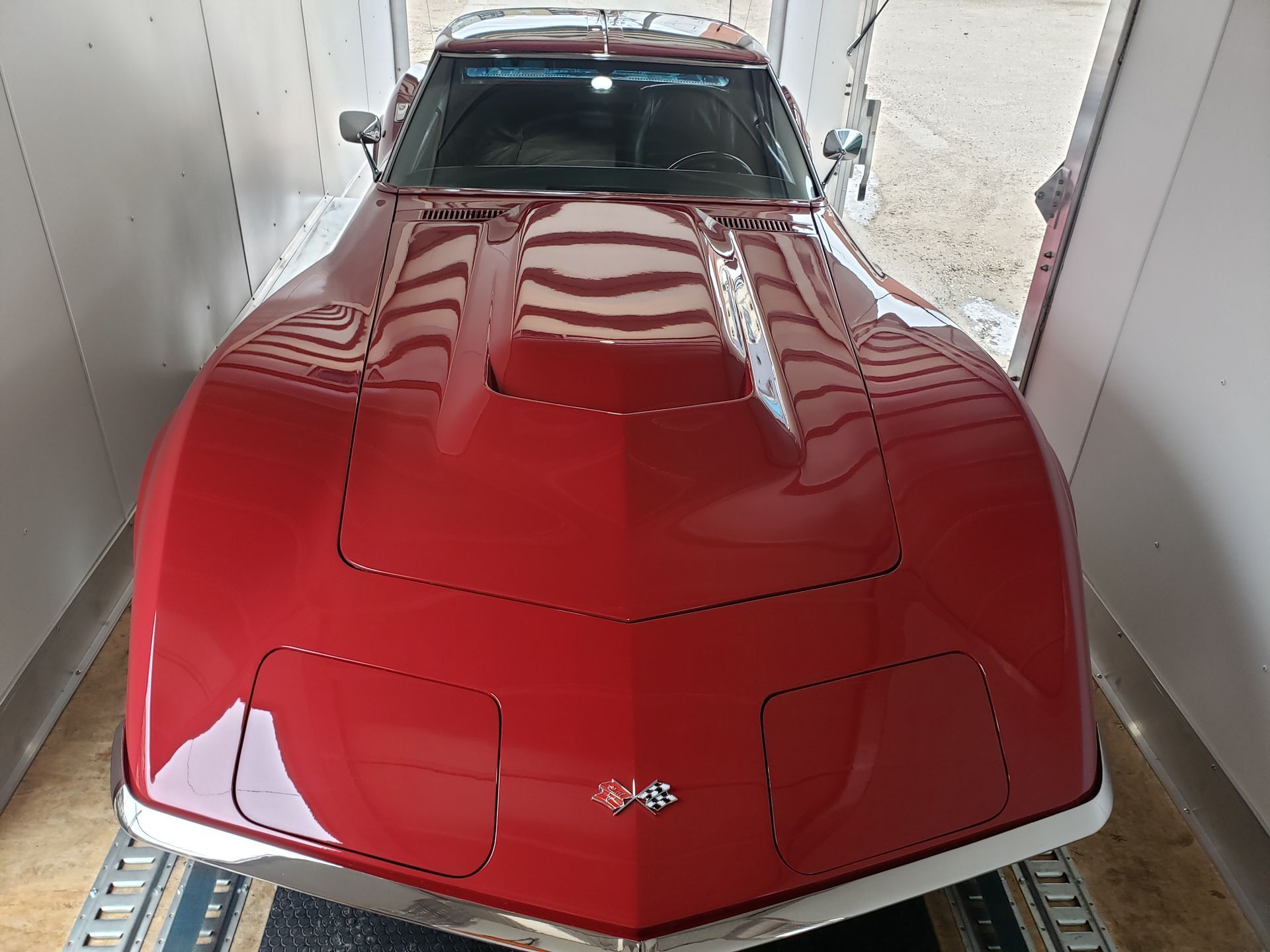 A red chevrolet corvette is parked in a garage