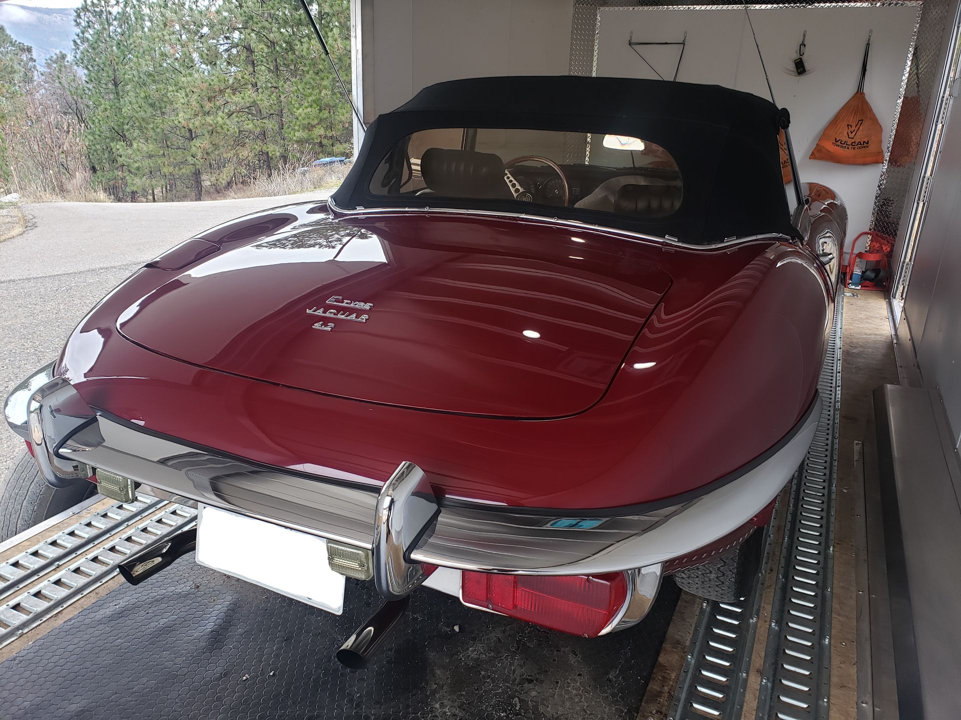 A red car with a black top is parked in a trailer.
