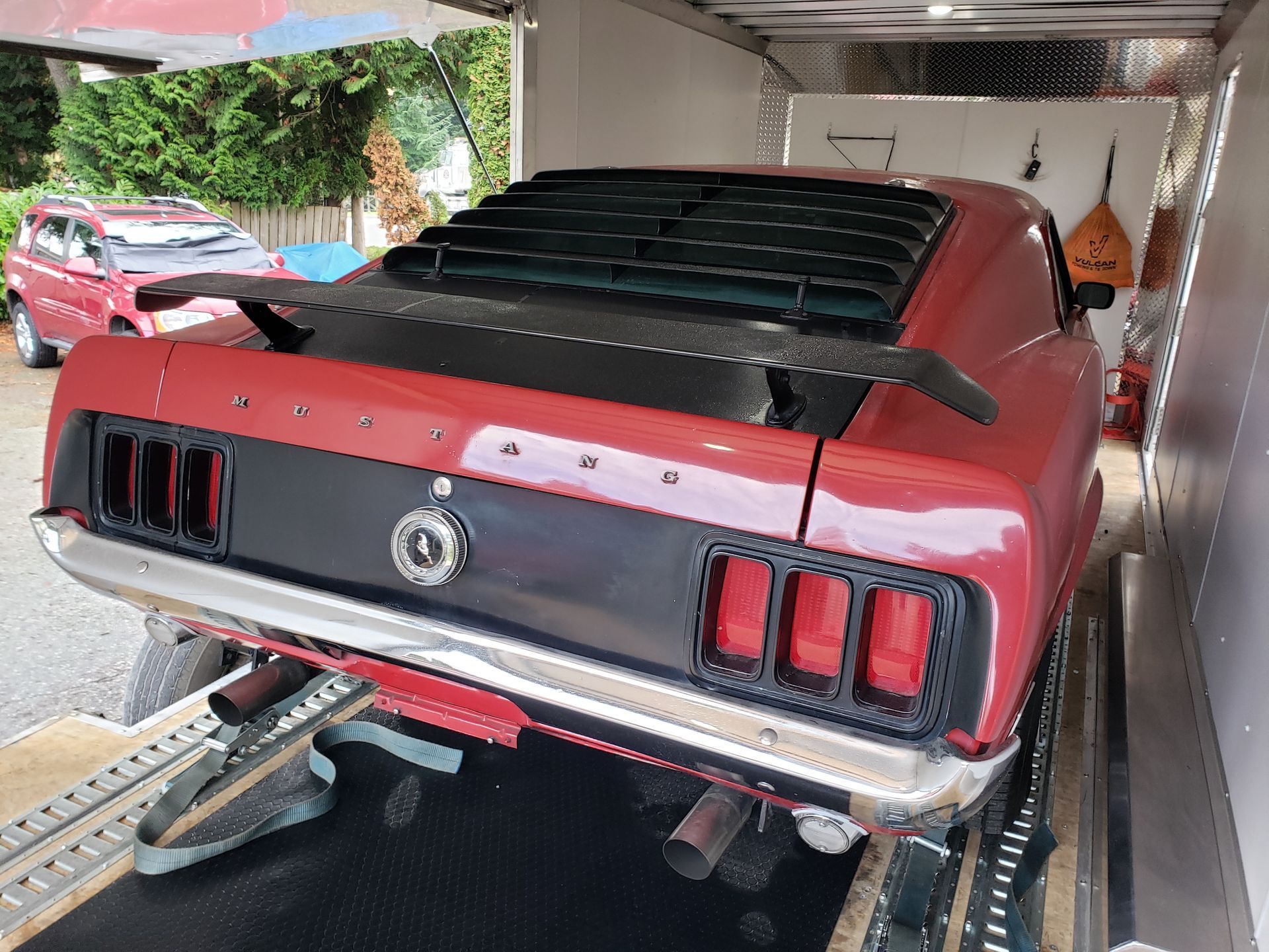 A red mustang is parked in a trailer.