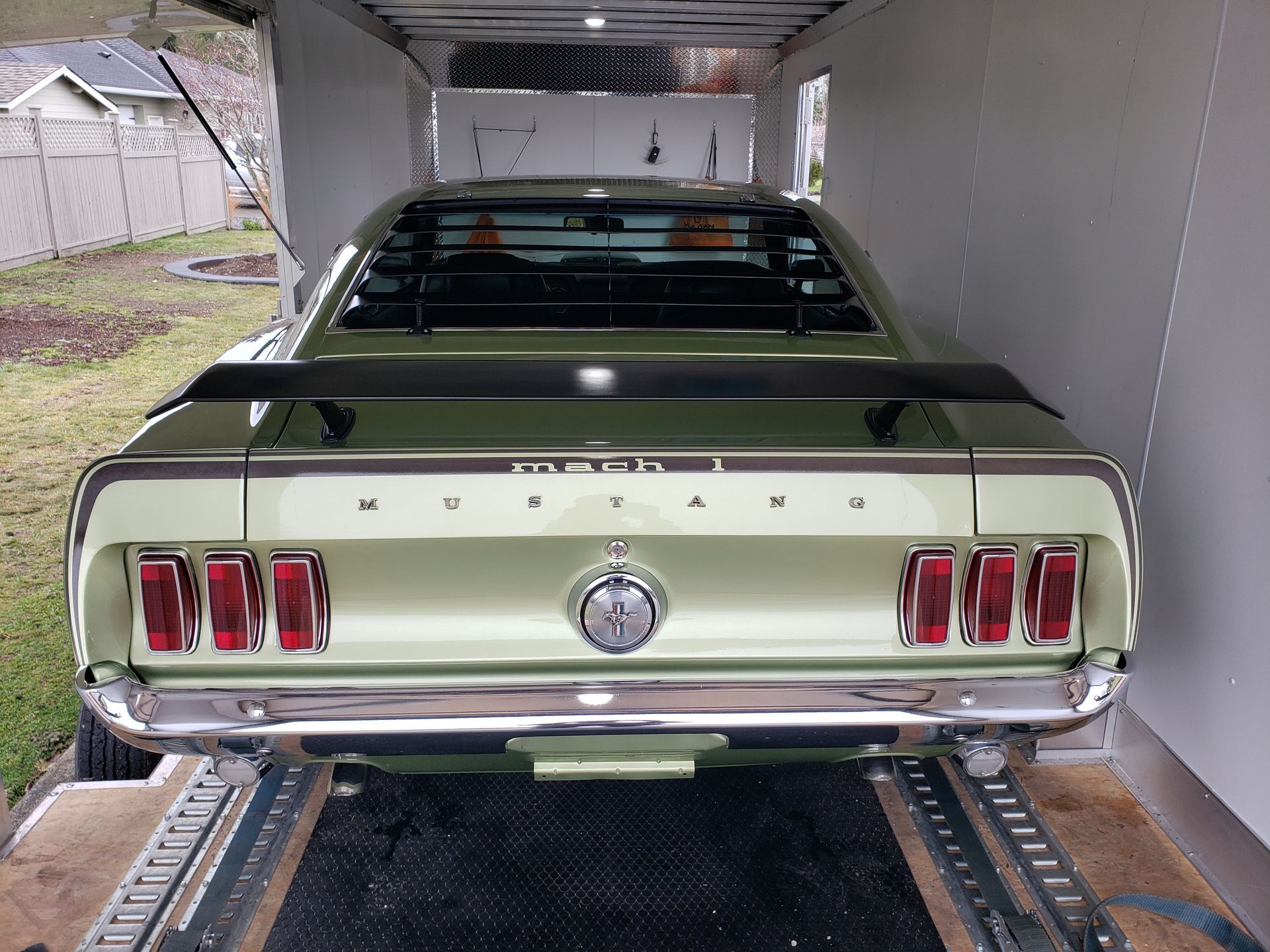 A green mustang is parked in a trailer