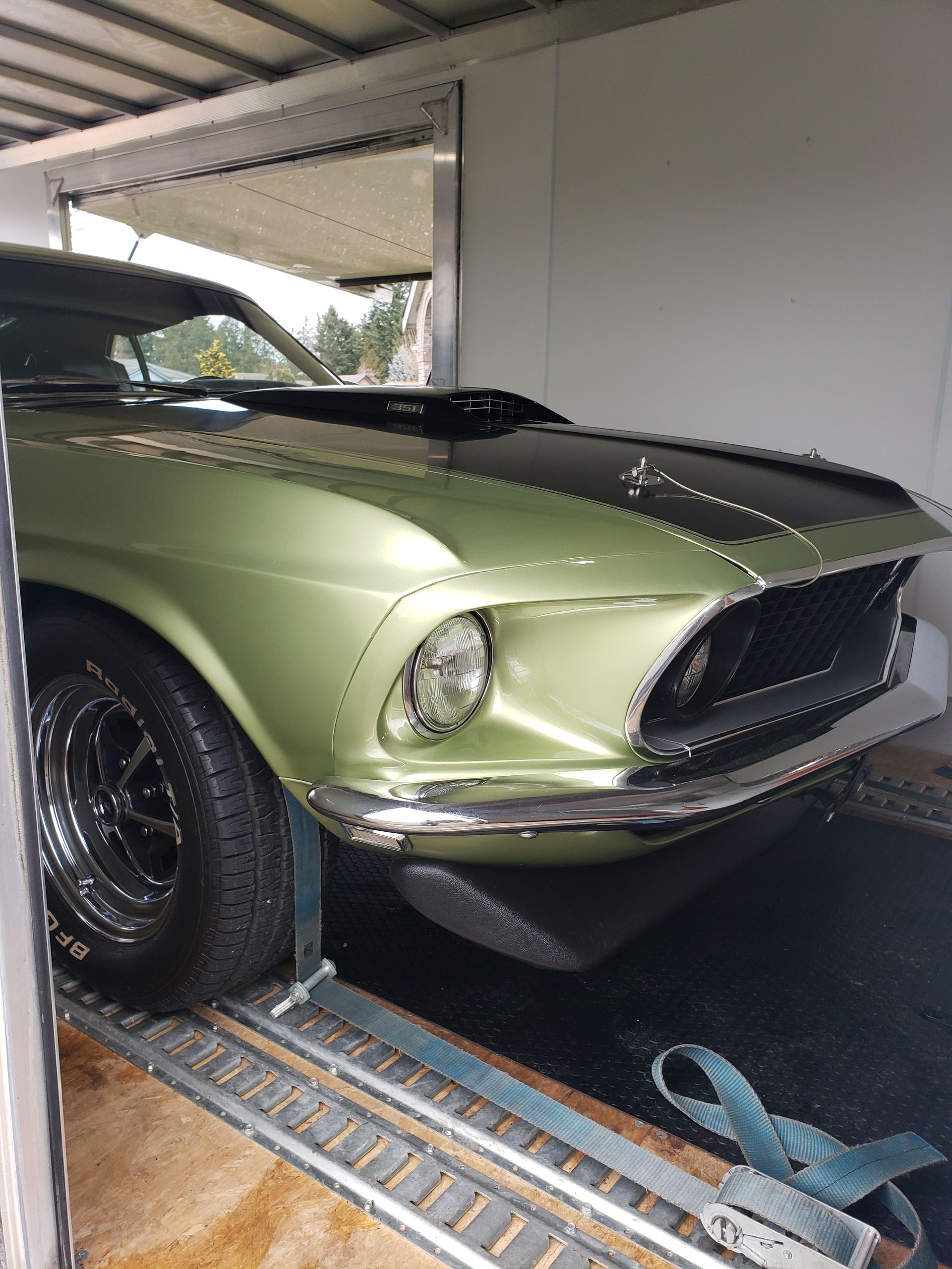 A green mustang is parked in a trailer