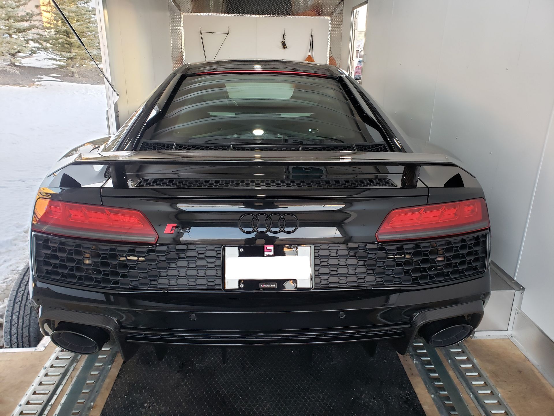 A black audi r8 is parked in a trailer.