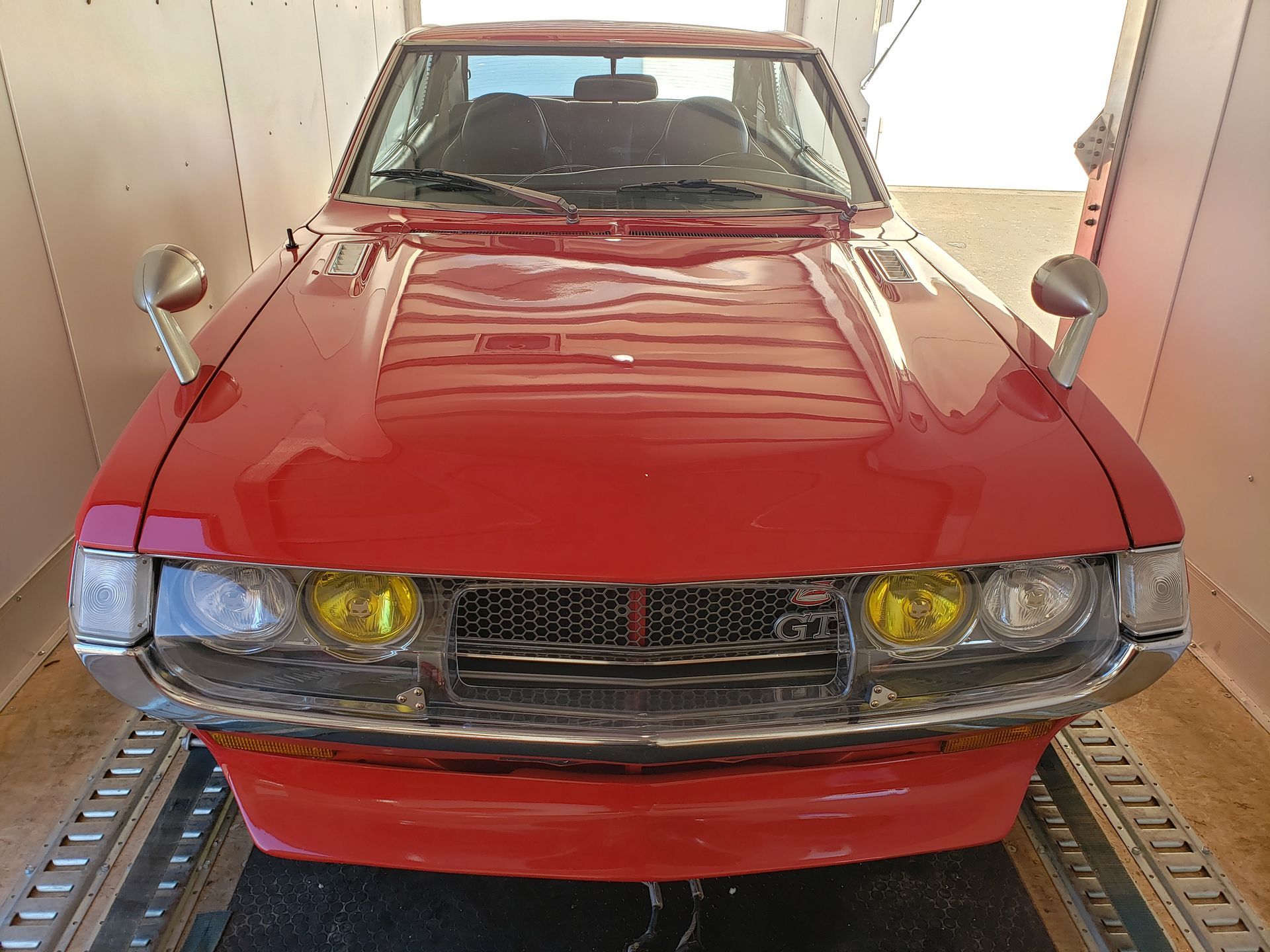 A red car with yellow lights is parked in a garage