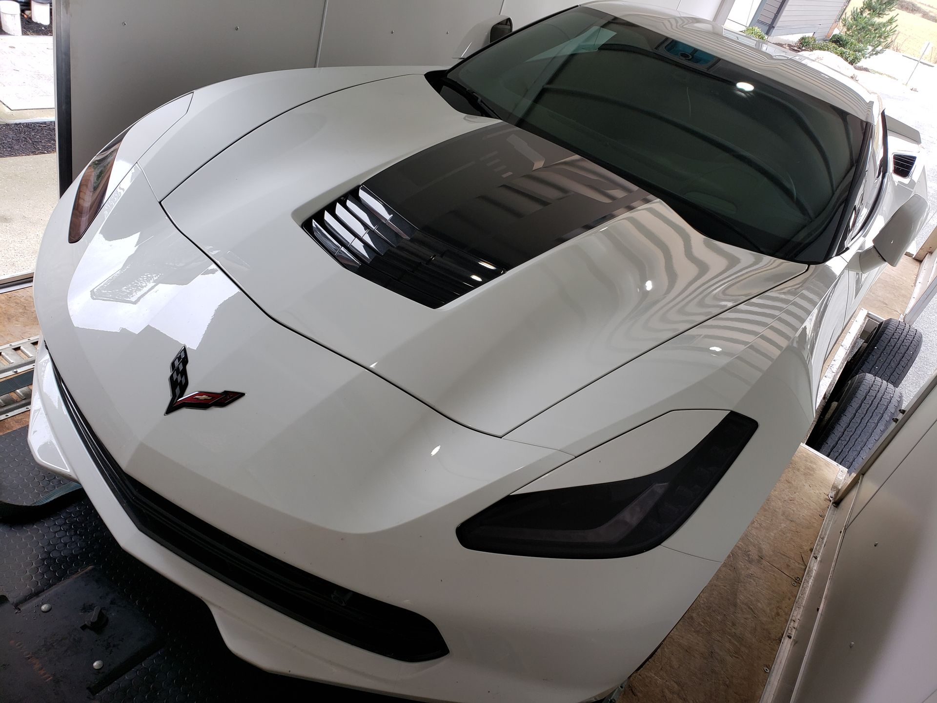 A white sports car is parked in a trailer.
