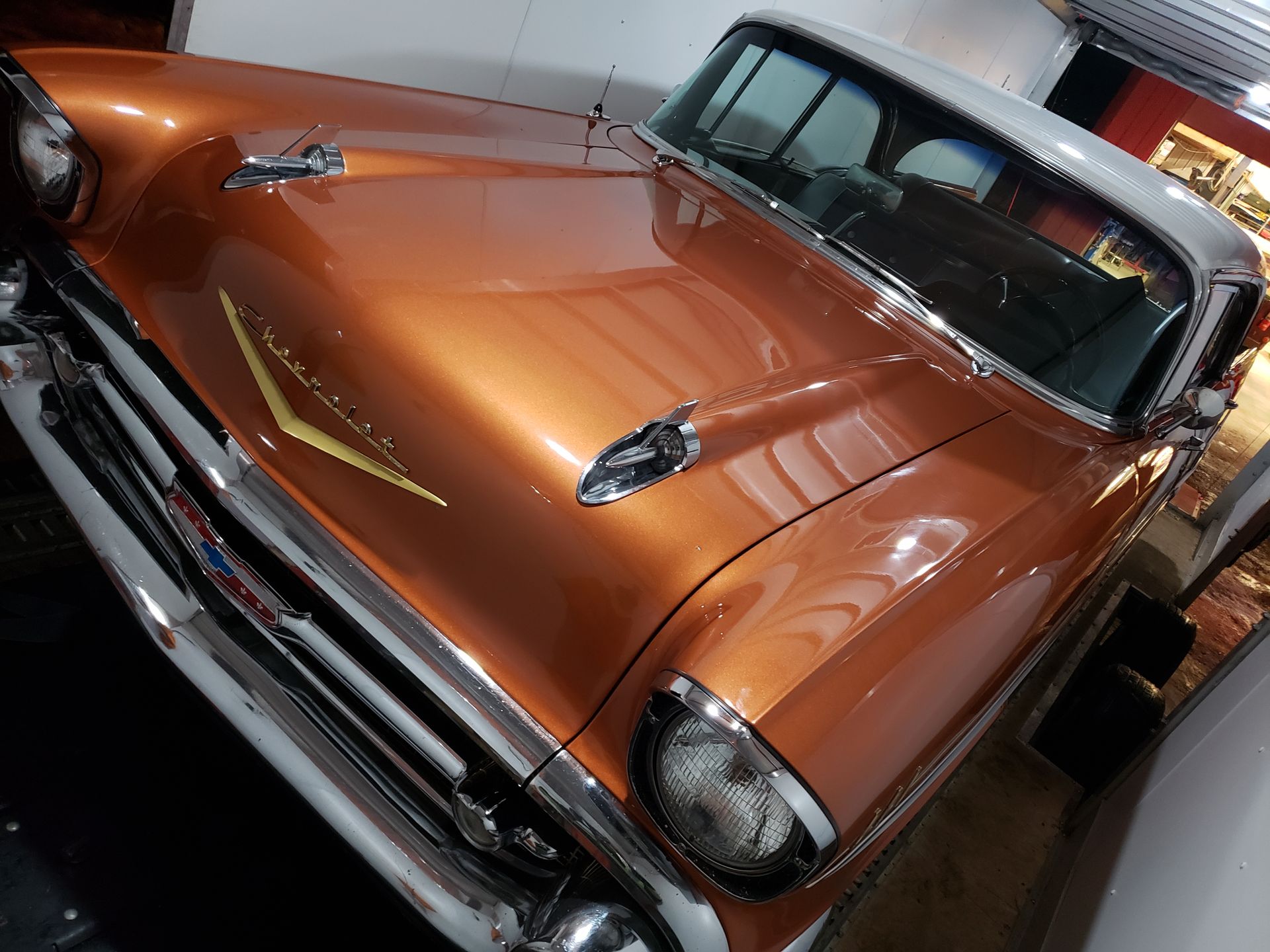 An old orange car with a yellow stripe on the hood