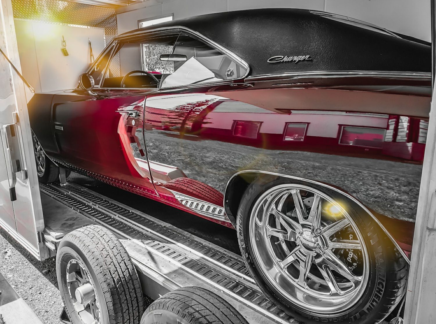 A red dodge charger is sitting on top of a trailer.
