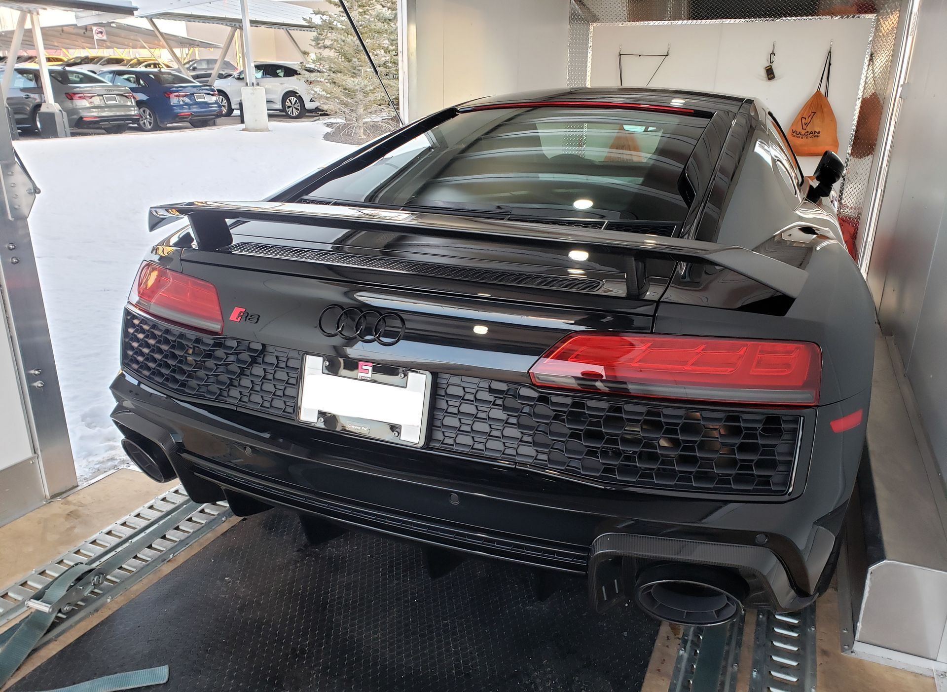 A black sports car is sitting on top of a trailer.