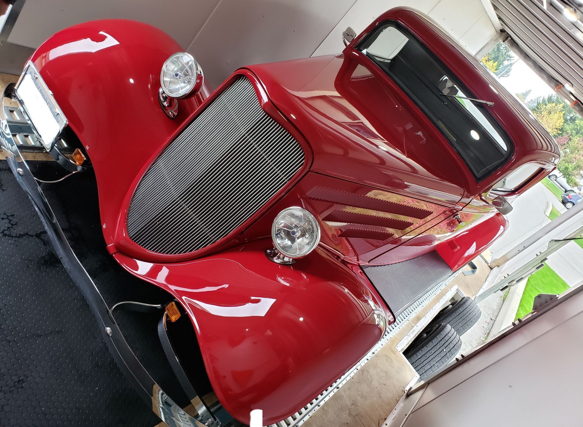 A red car is sitting on a trailer in a garage