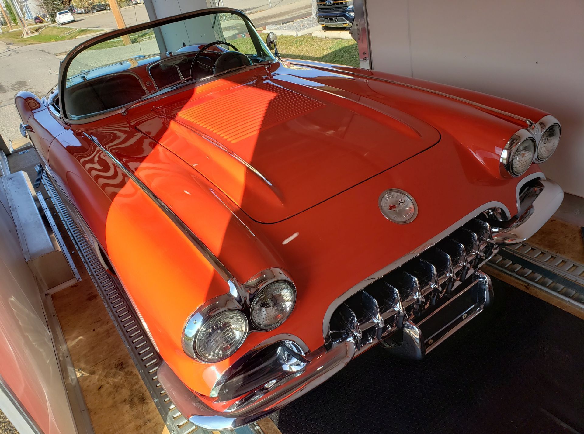 A red corvette convertible is parked in a garage.