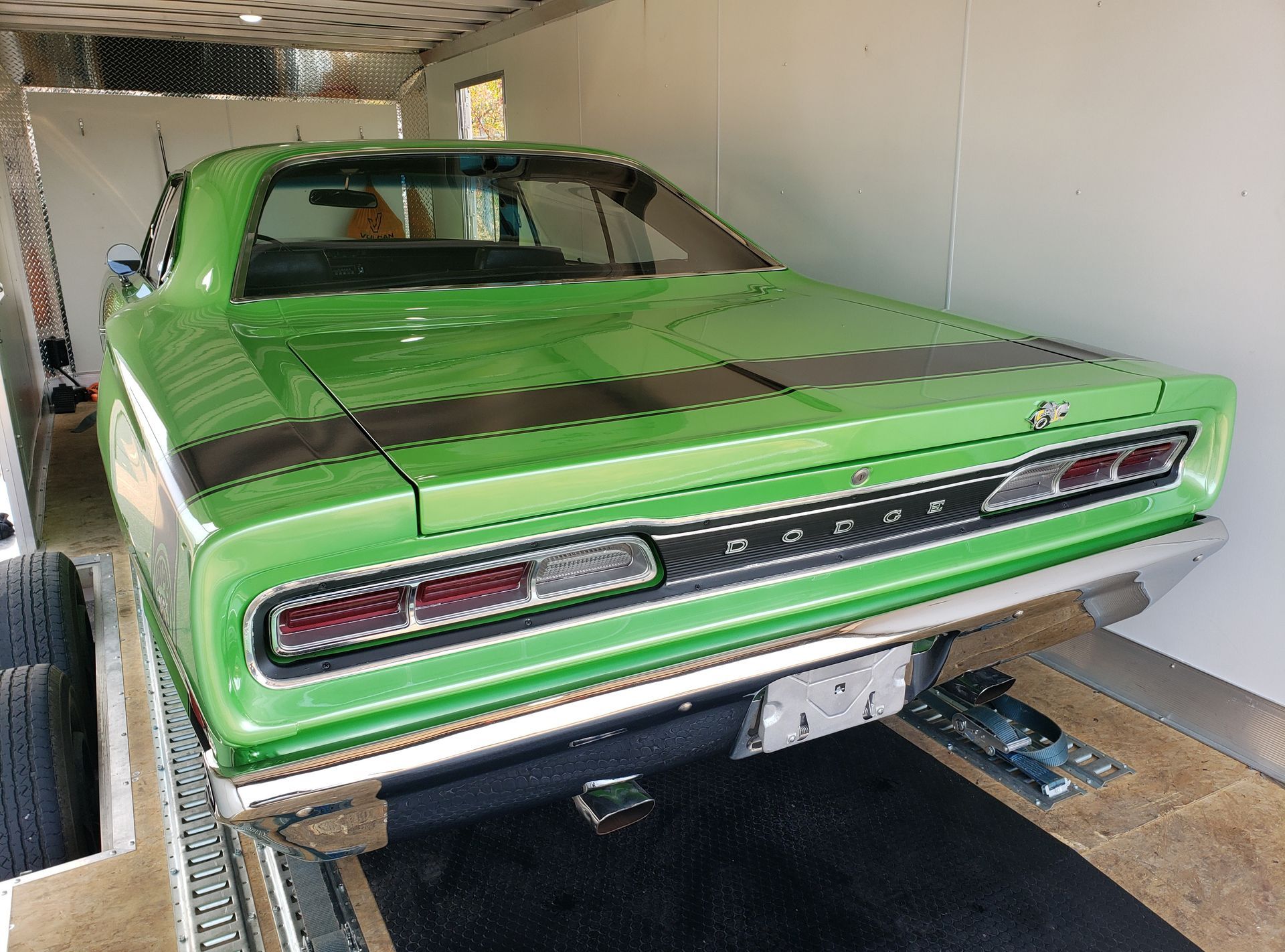 A green dodge charger is parked in a trailer.