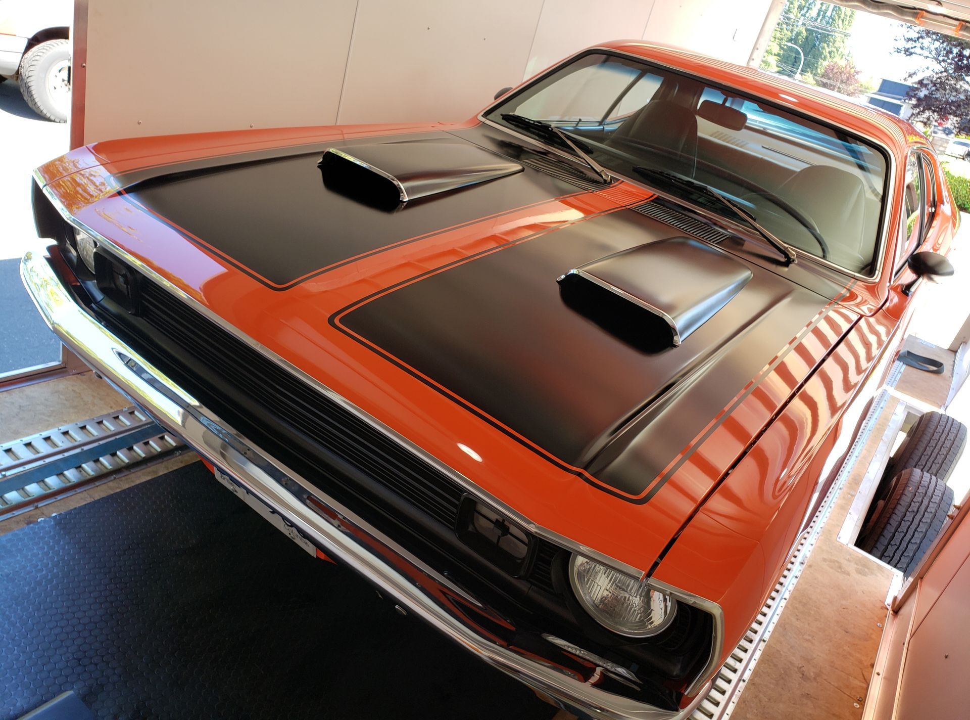 An orange and black muscle car is parked in a garage