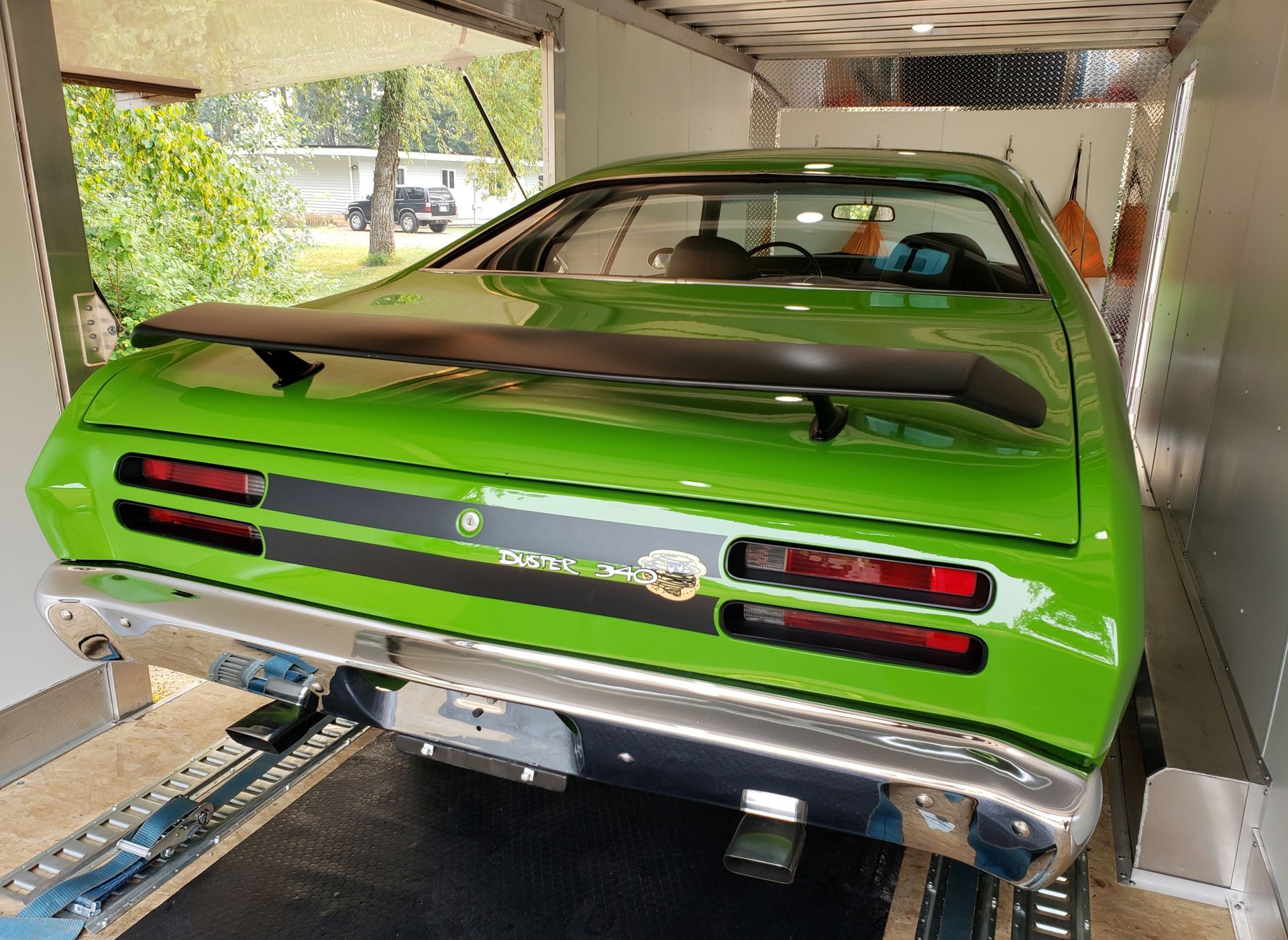 A green car is parked in a garage on a trailer.