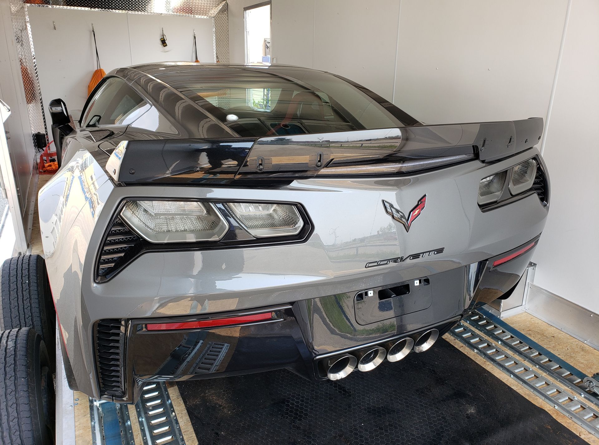 A gray corvette is parked in a garage.