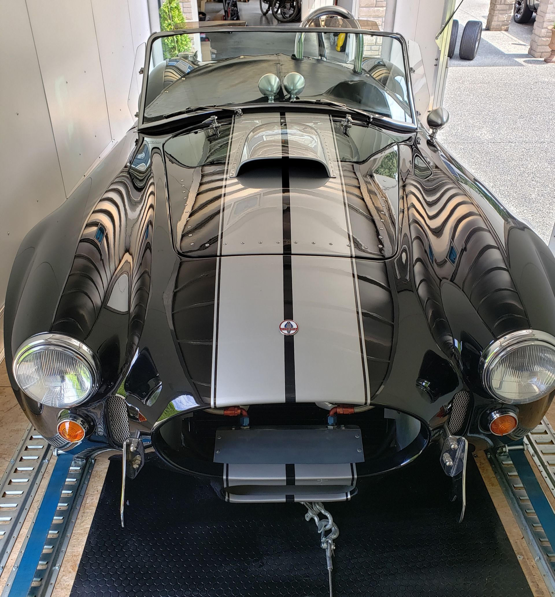 A black and silver sports car is parked in a garage