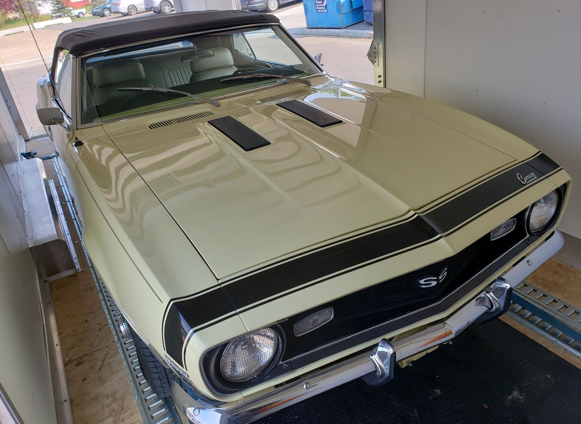 A yellow chevrolet camaro convertible is parked in a garage.