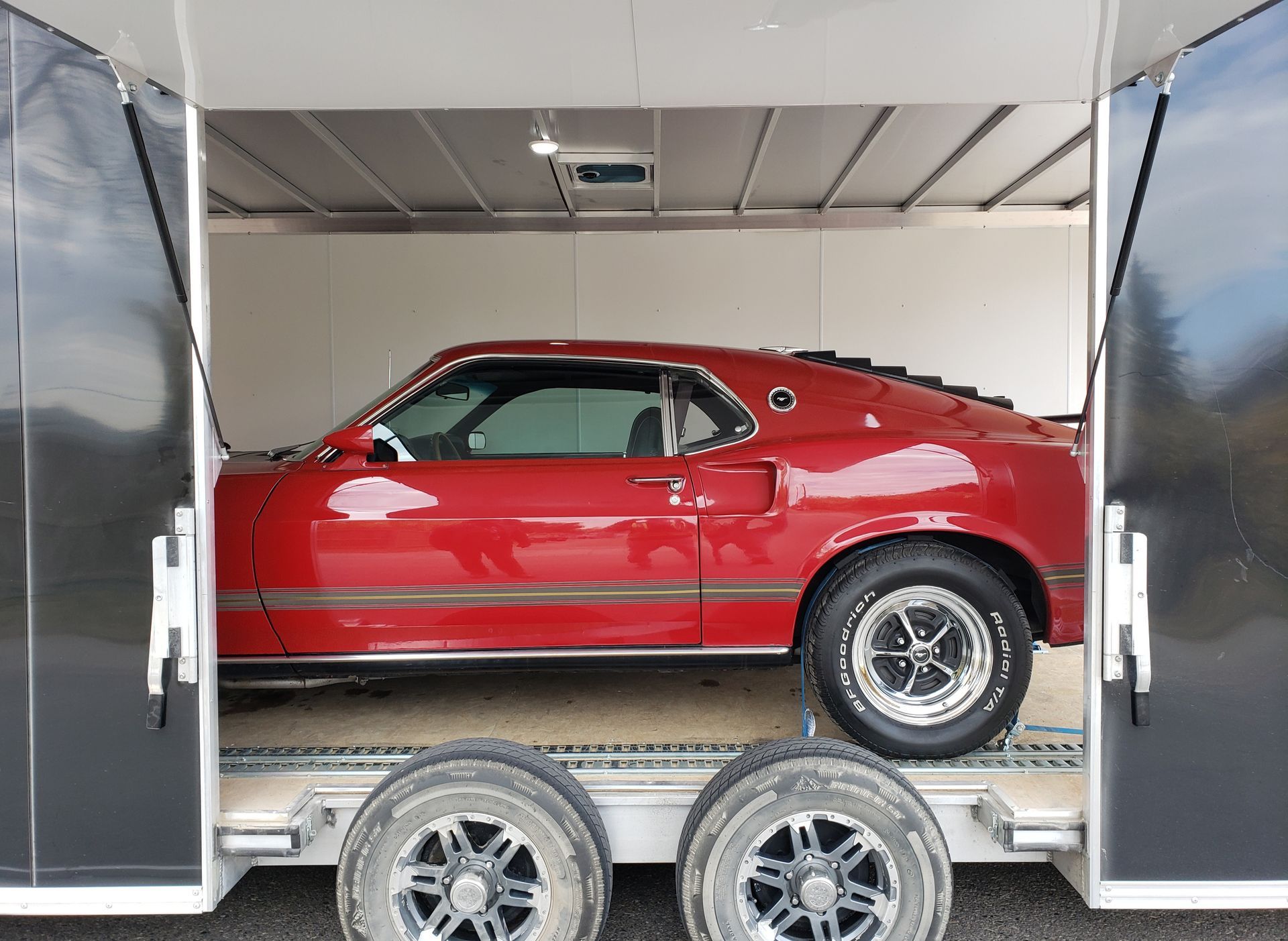 A red mustang is parked in the back of a trailer.