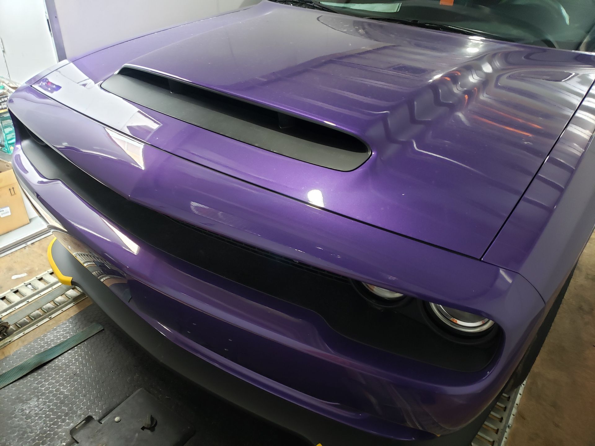 A purple dodge challenger is parked in a garage.
