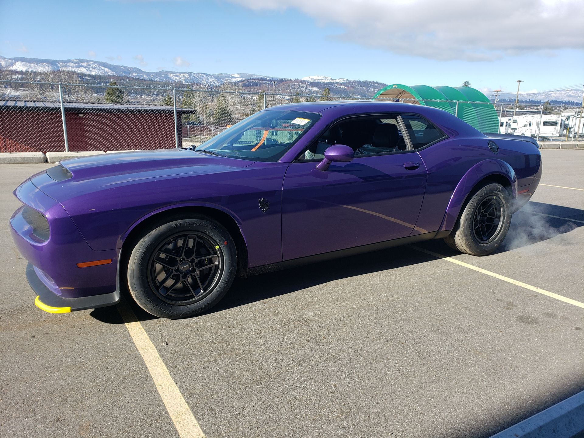 A purple dodge challenger is parked in a parking lot.