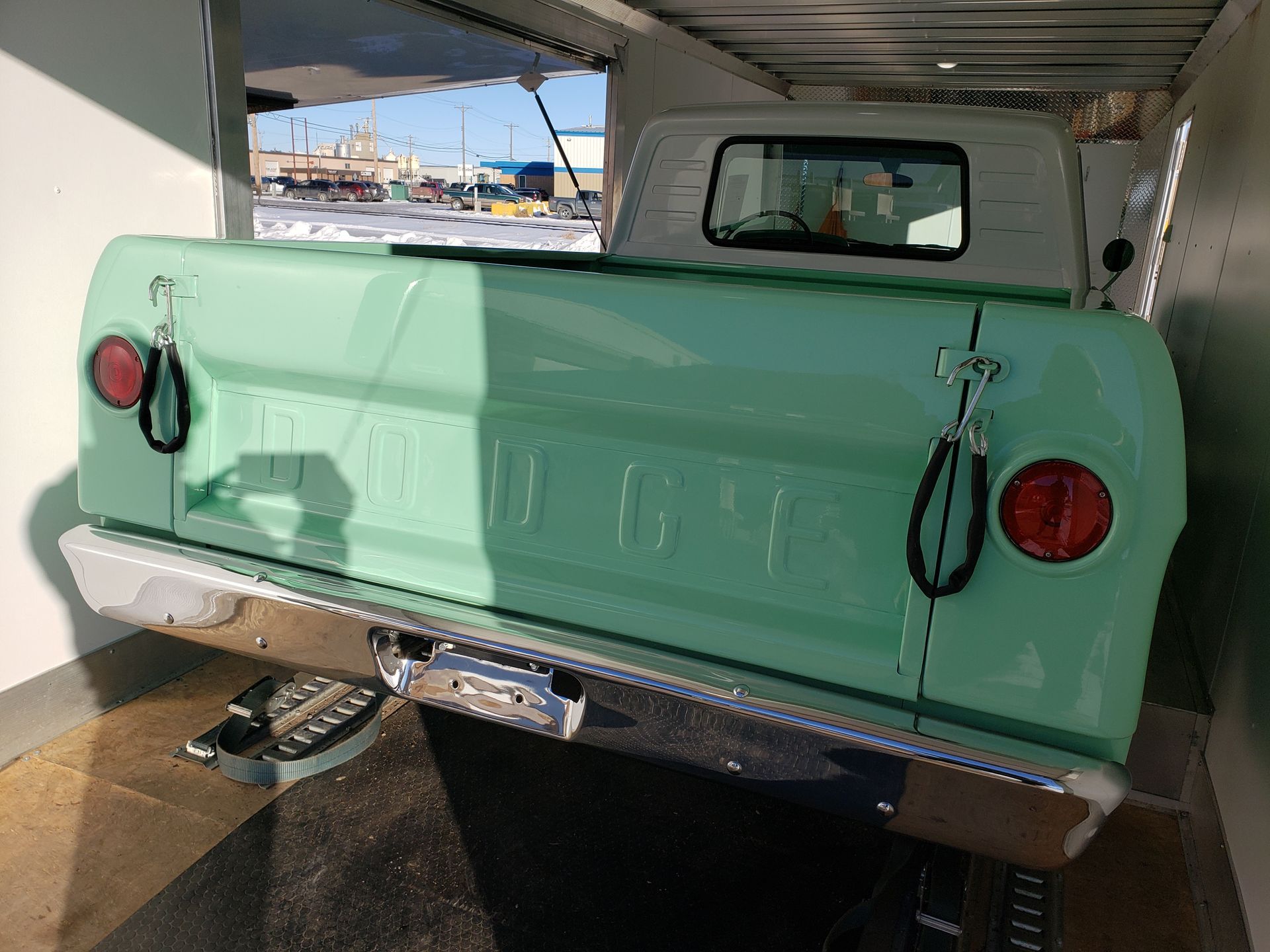 A green pickup truck is parked in a trailer.