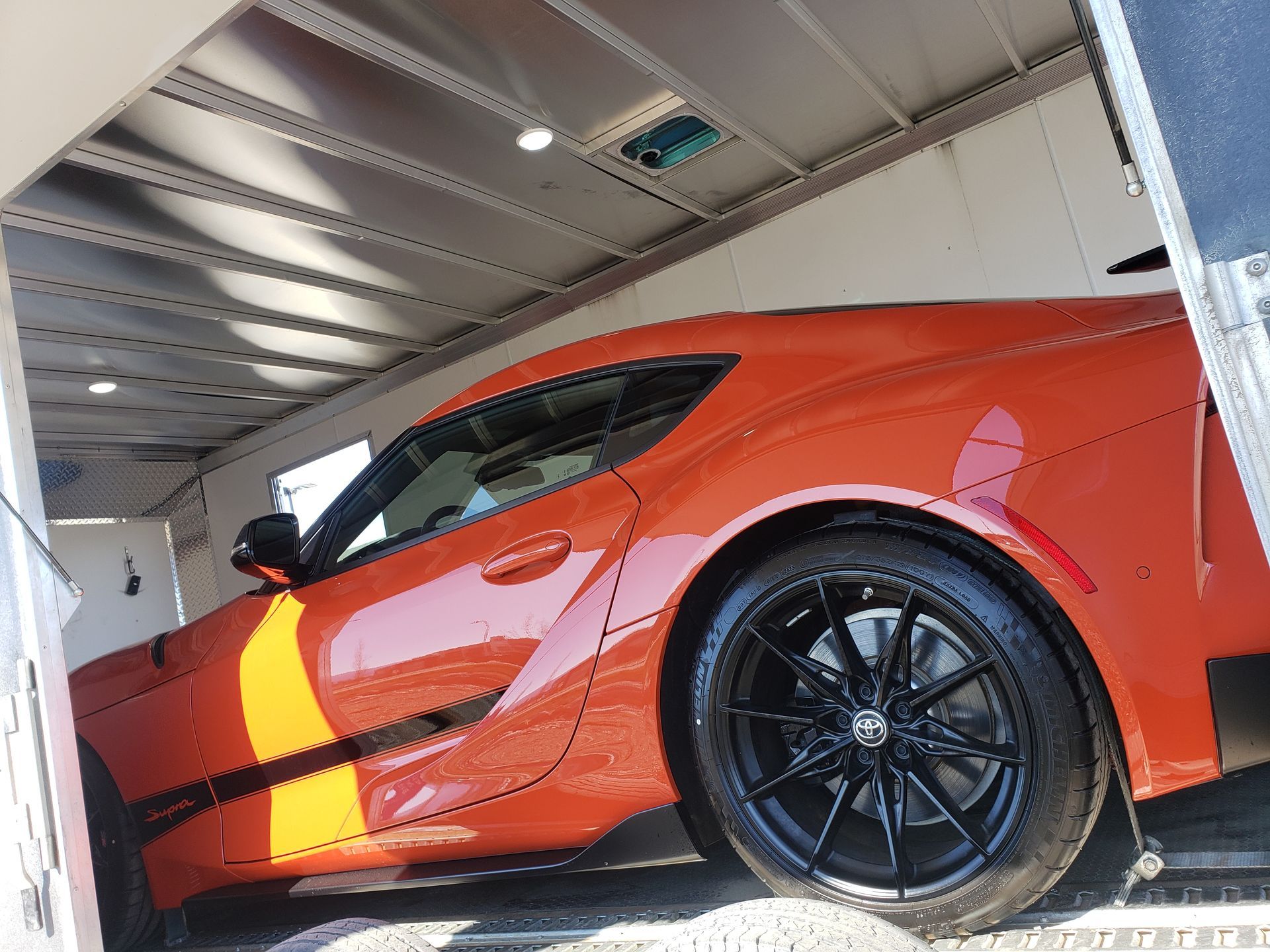 A red sports car is sitting inside of a trailer.