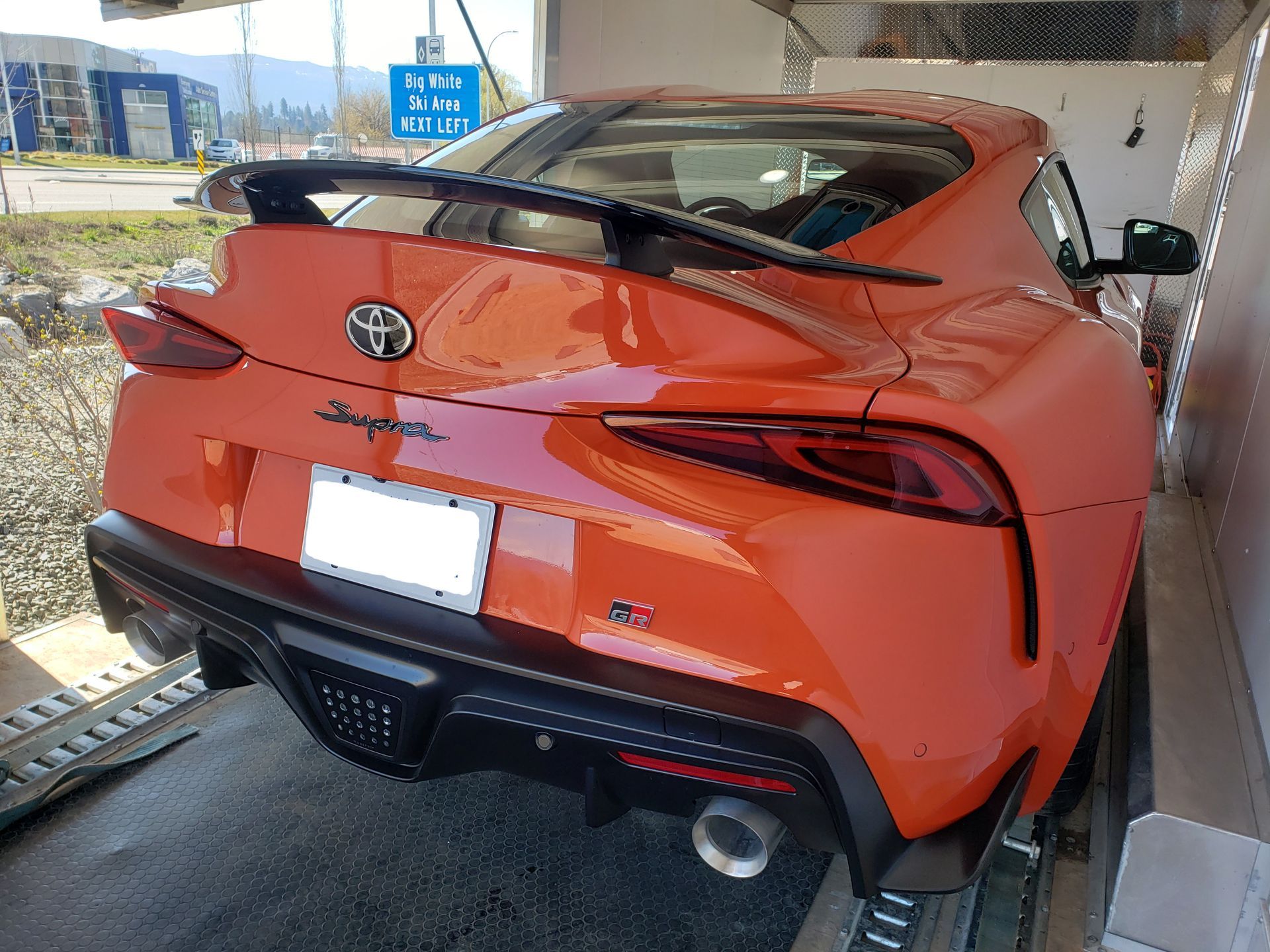 An orange toyota supra is parked in a garage.