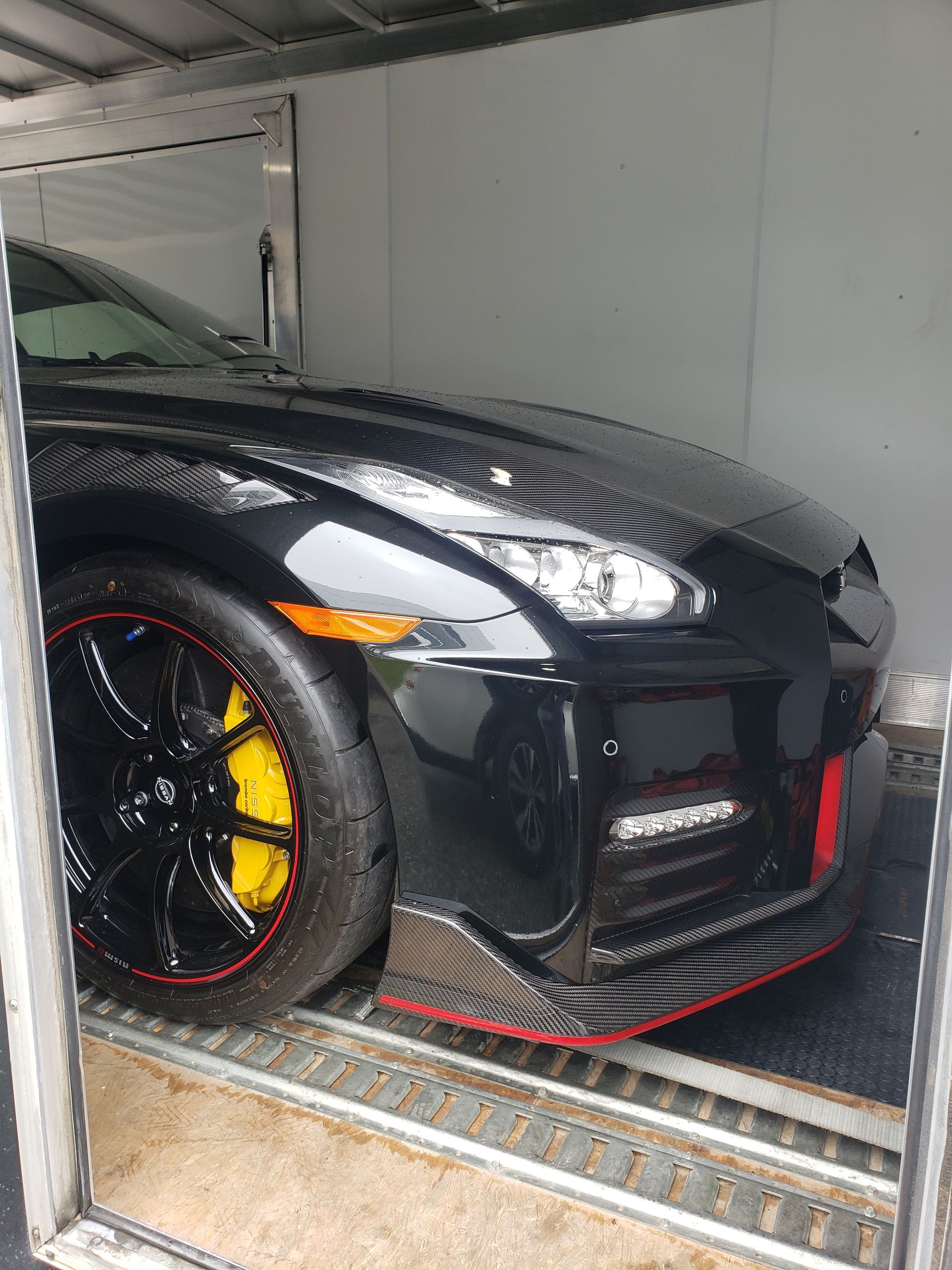 A black sports car is parked in a trailer.