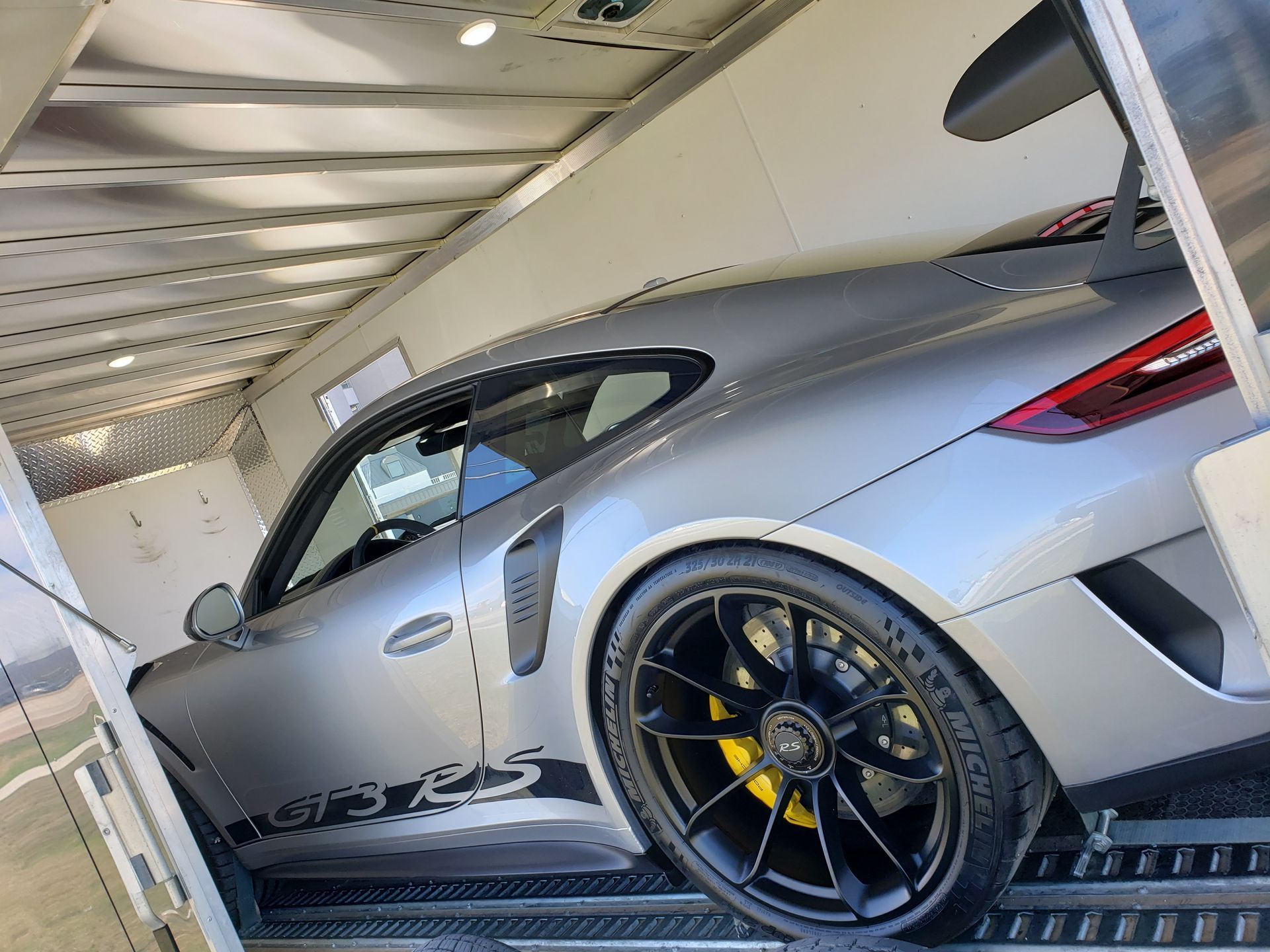 A porsche 911 gt3 rs is sitting inside of a trailer.
