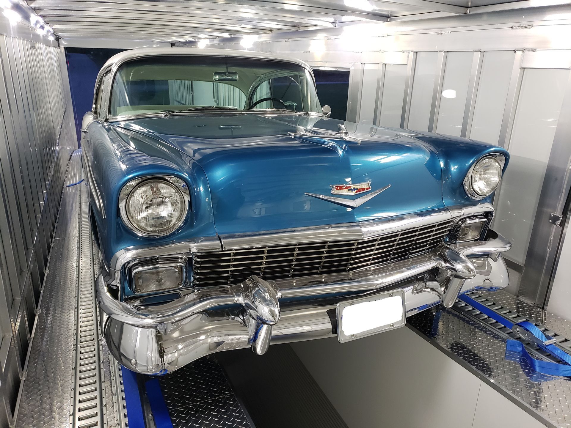 A blue cadillac is parked in a garage.