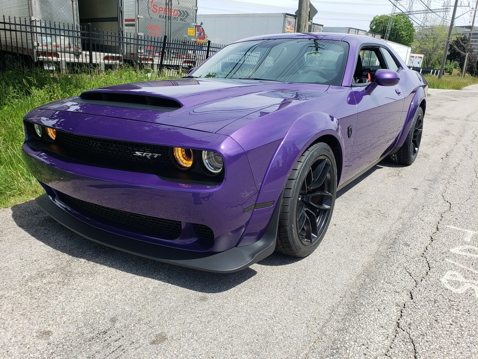 A purple dodge challenger demon is parked on the side of the road.