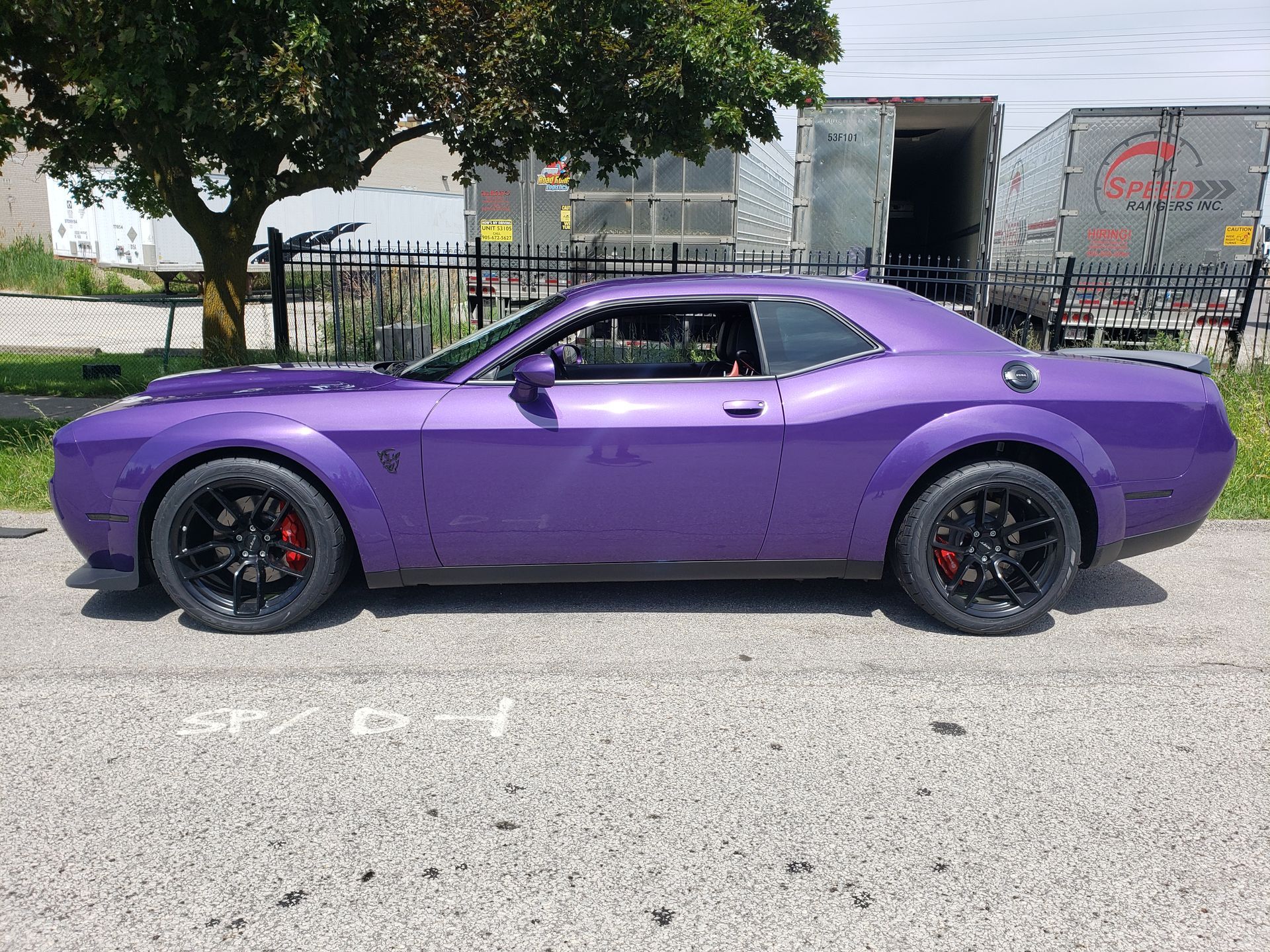 A purple dodge challenger is parked on the side of the road.