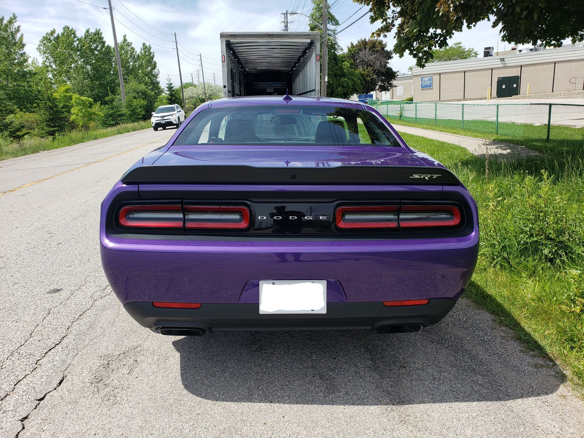 A purple dodge challenger is parked on the side of the road