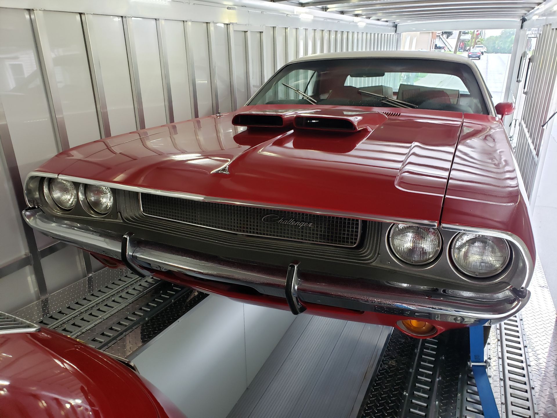A red dodge challenger is parked in a trailer.