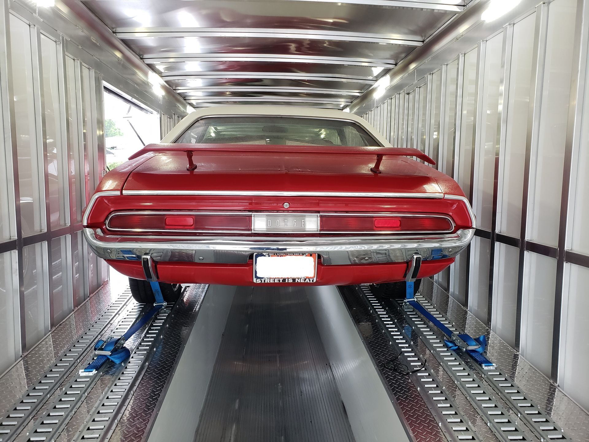 A red car is sitting inside of a trailer.