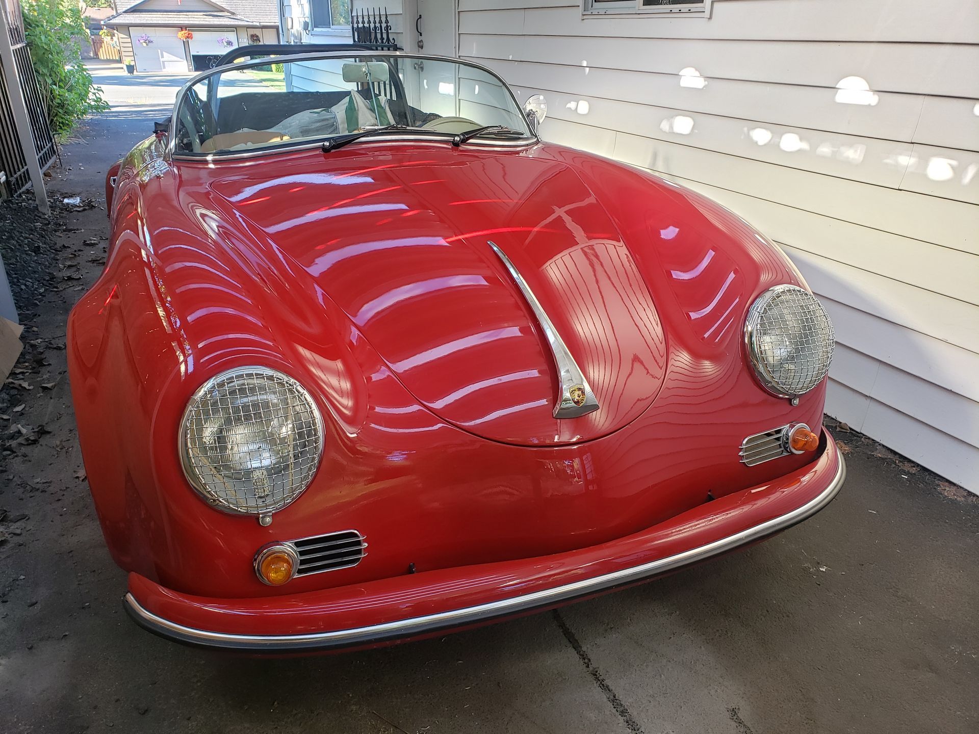A red sports car is parked in front of a white house