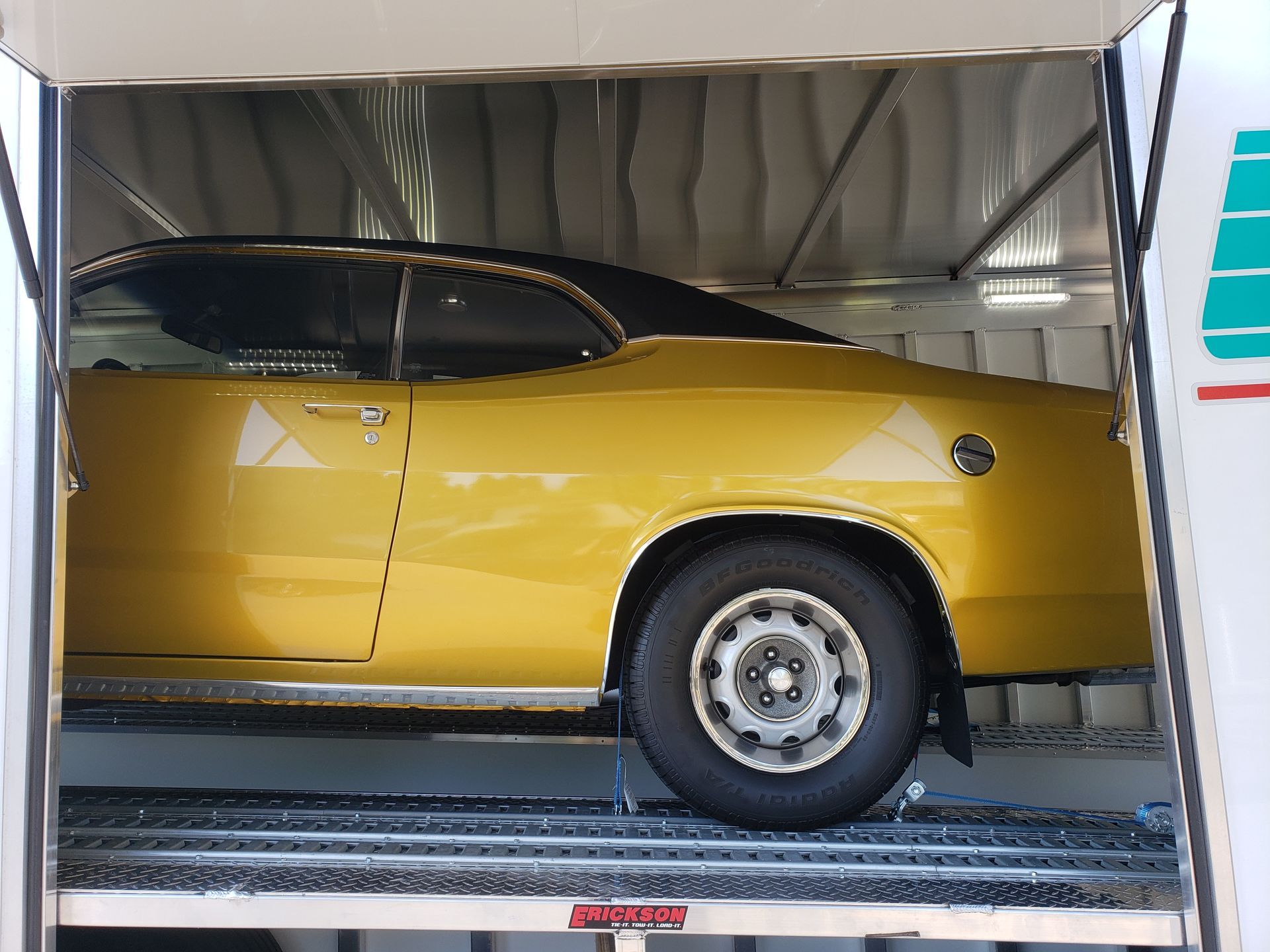 A yellow car is sitting inside of a trailer.