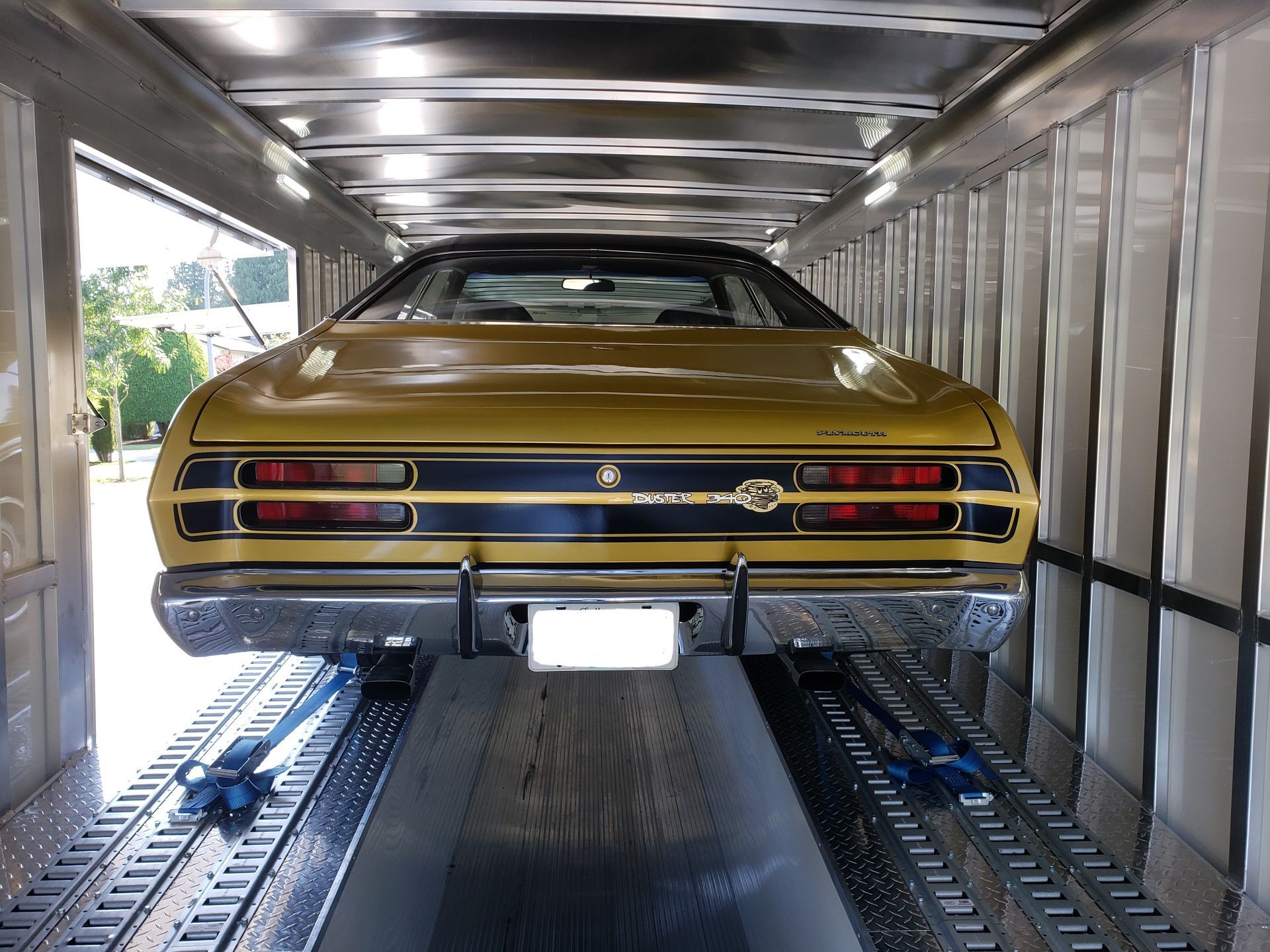 A yellow car is sitting inside of a trailer