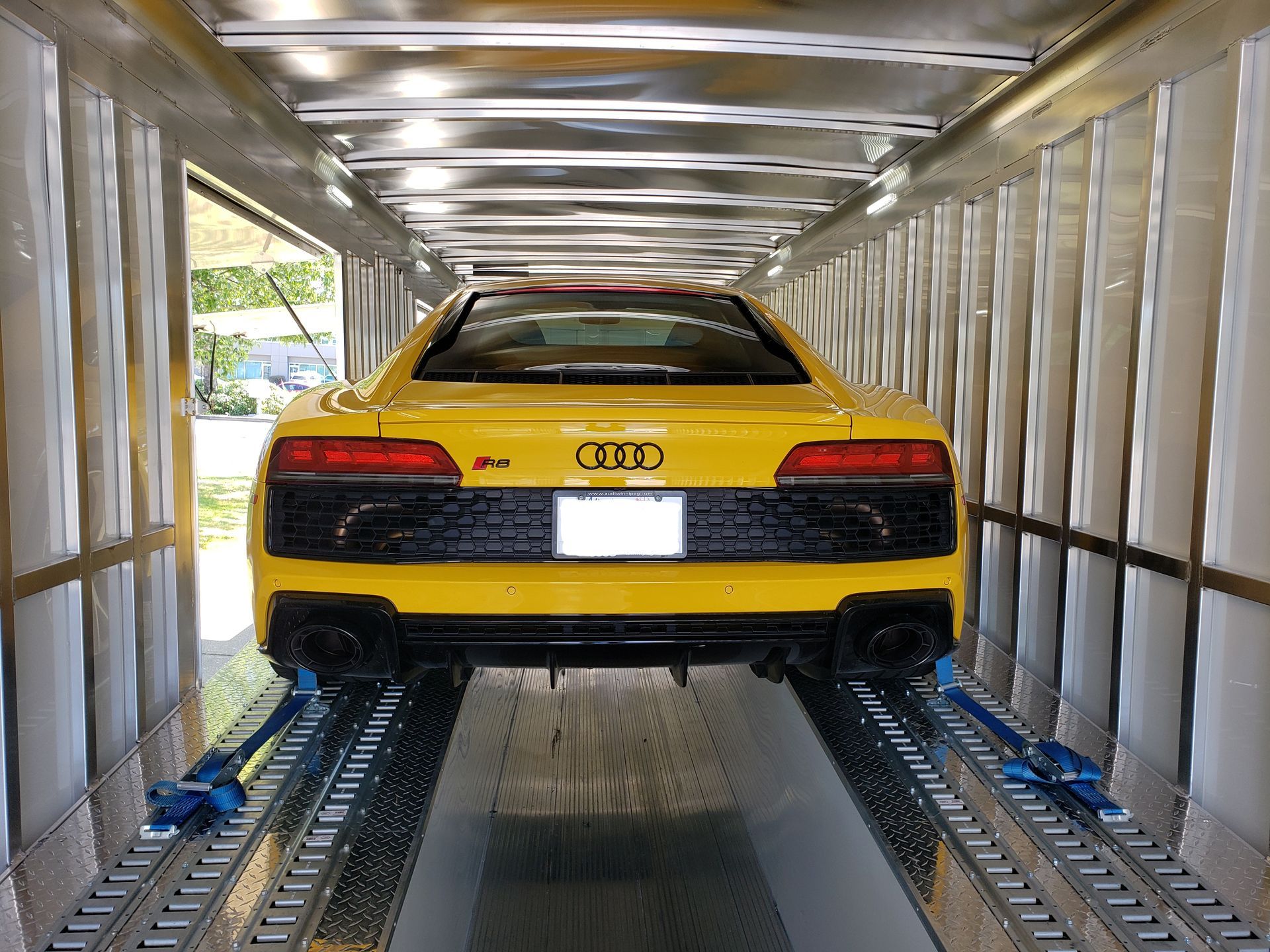 A yellow audi r8 is being transported in a trailer.