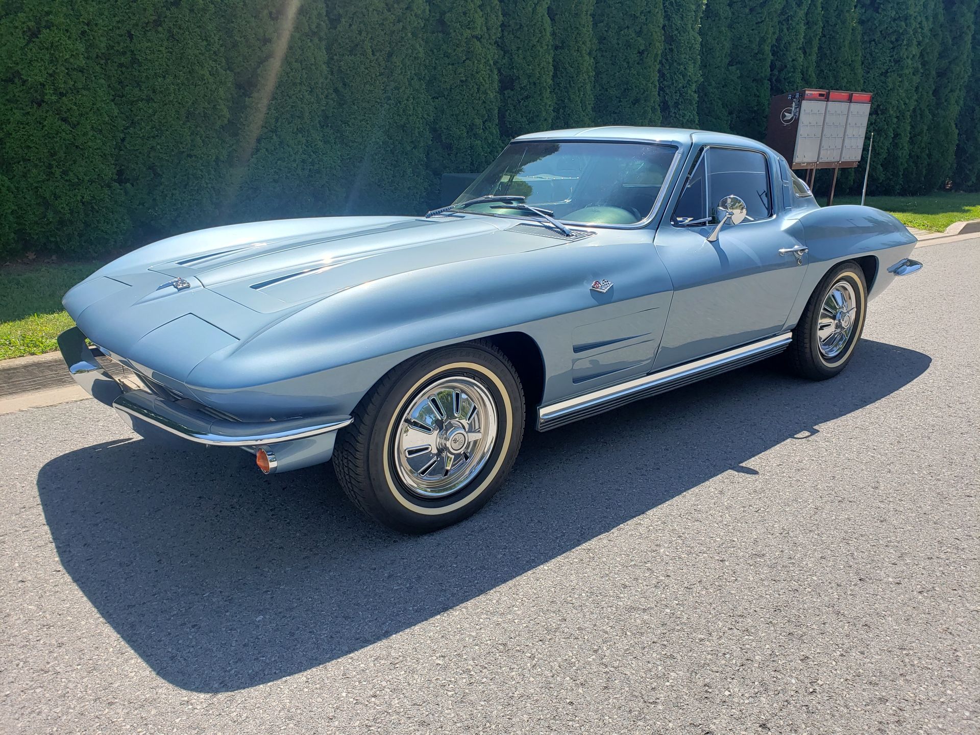 A blue corvette is parked on the side of the road.