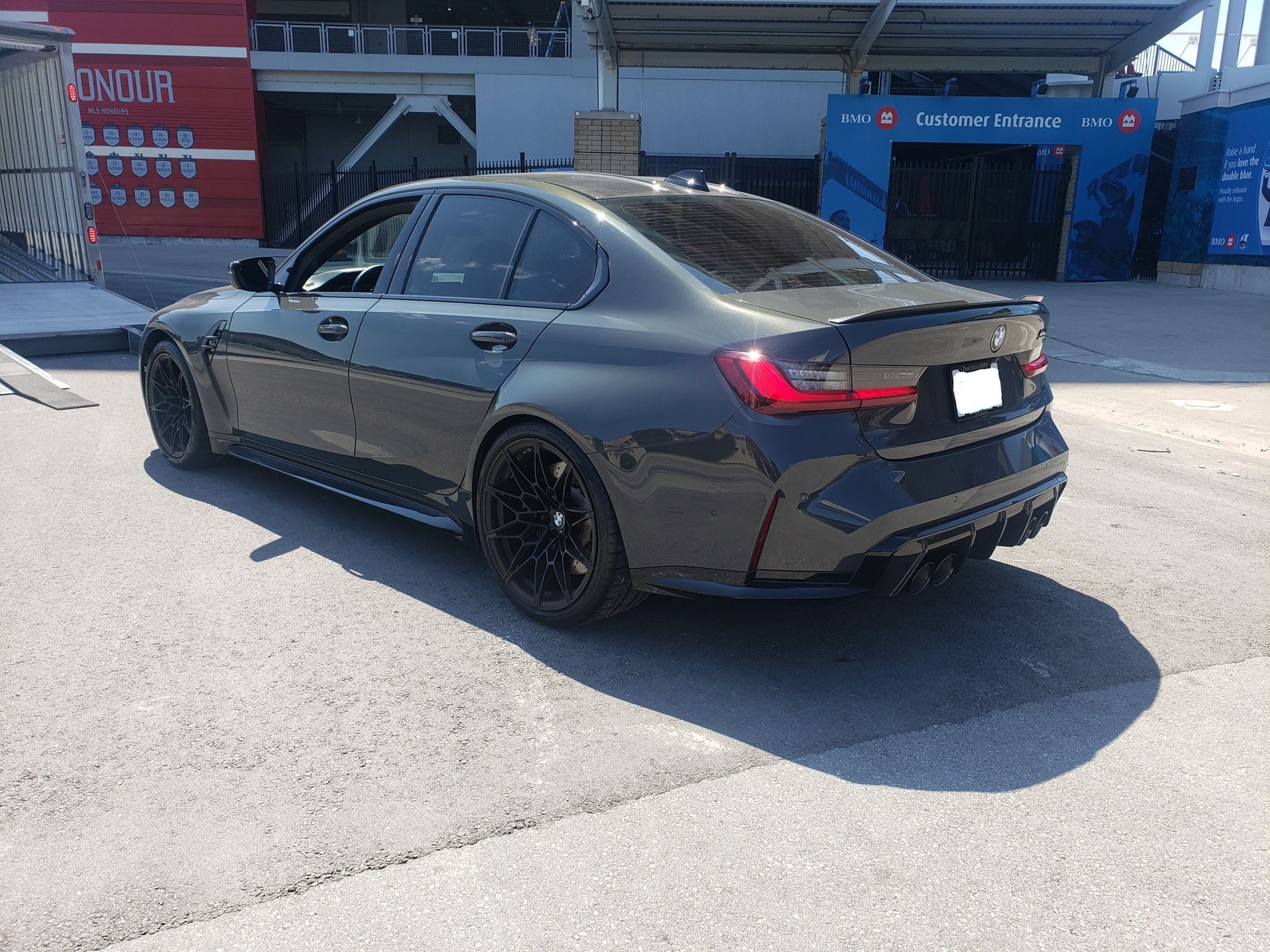 A black bmw m3 is parked on the side of the road in front of a building.