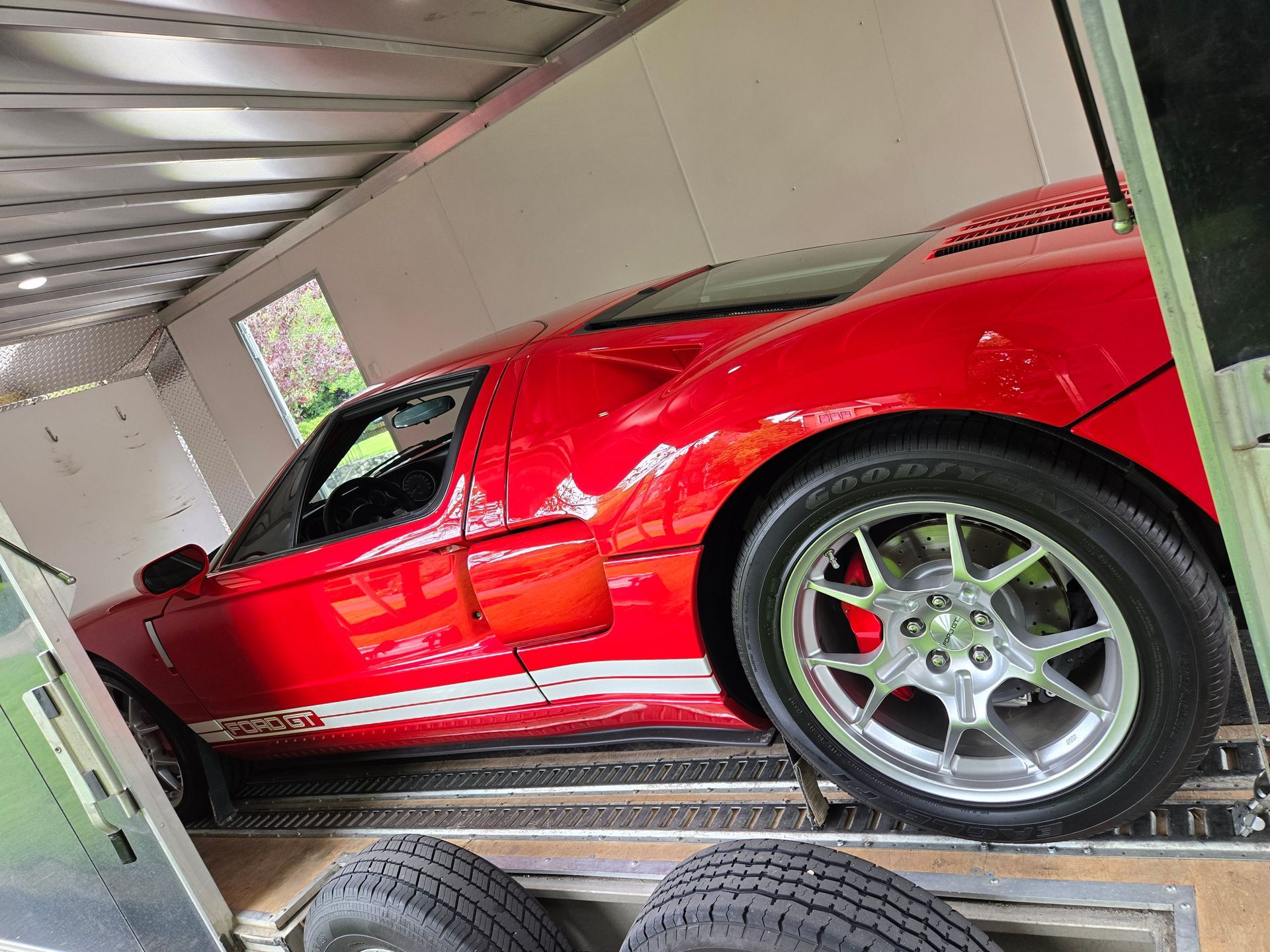 A red sports car is sitting on top of a trailer.