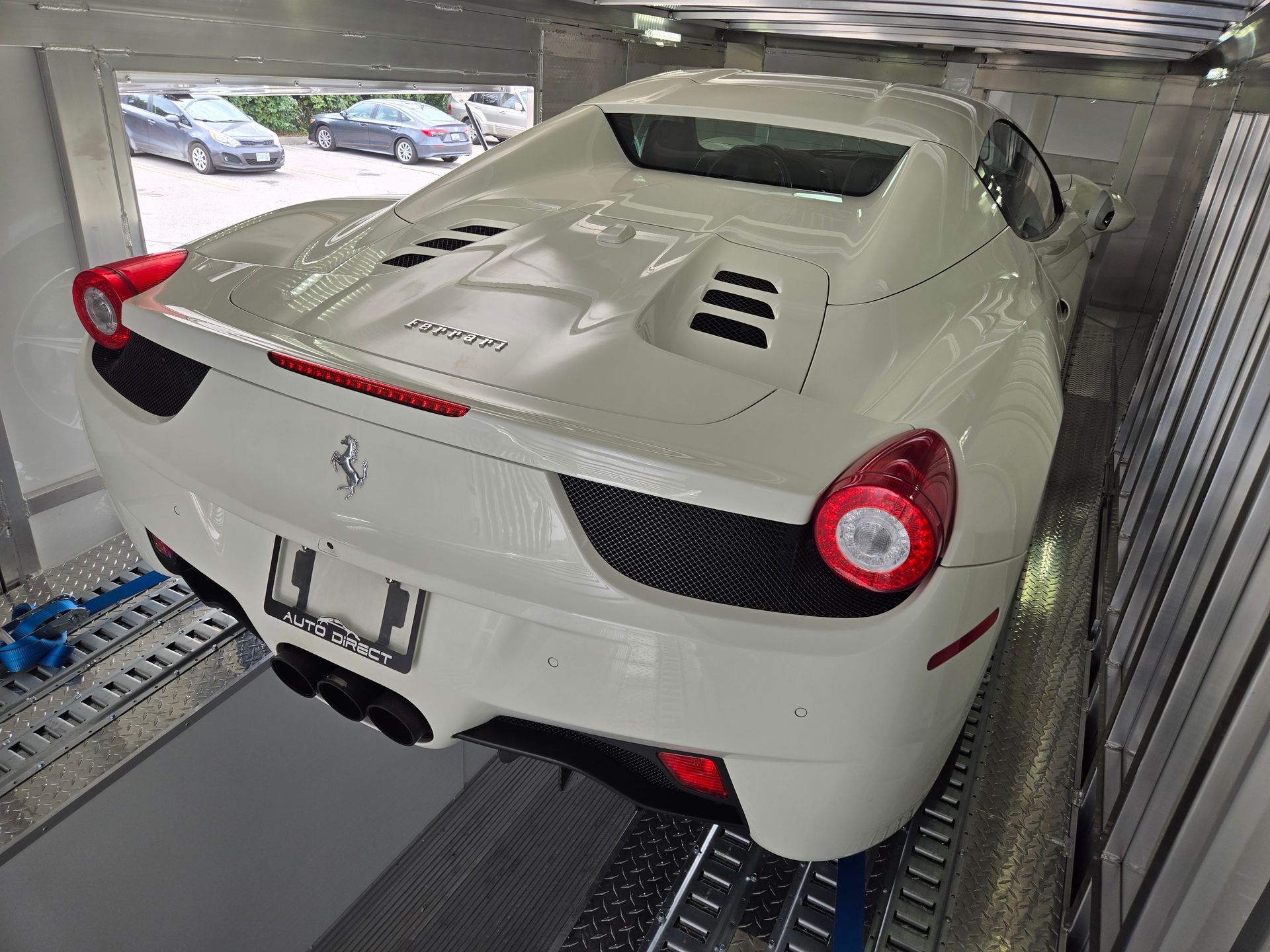 A white ferrari sports car is being transported on a trailer.