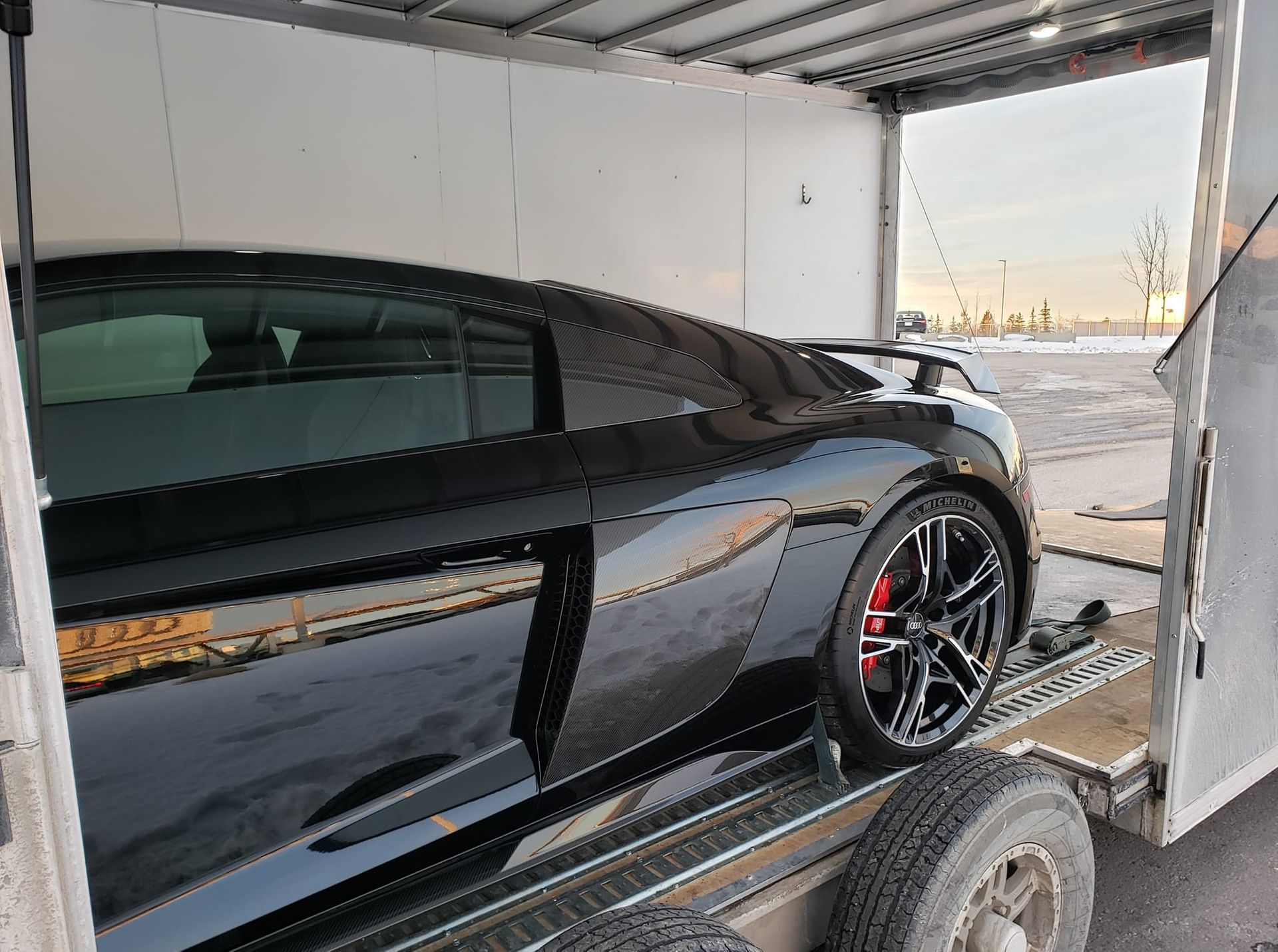 A black sports car is being transported on a trailer.