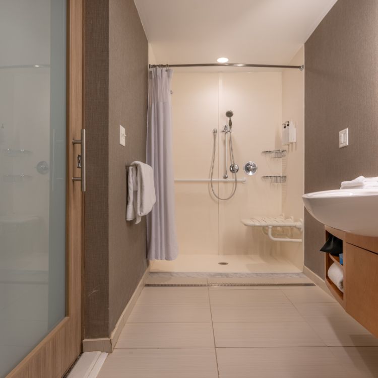 Accessible bathroom with a shower, sink, and safety features.
