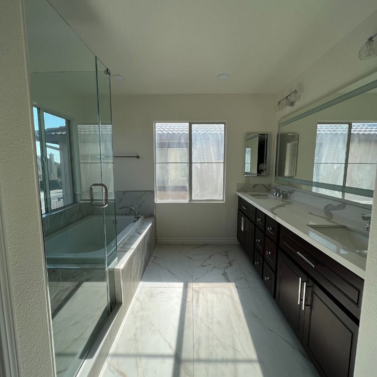 Bathroom with a bathtub, glass shower, double sink vanity, and a window. Bright and modern design.