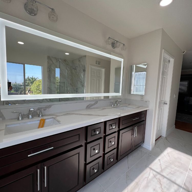 Bathroom with dark brown vanity, marble countertop, and large illuminated mirror.