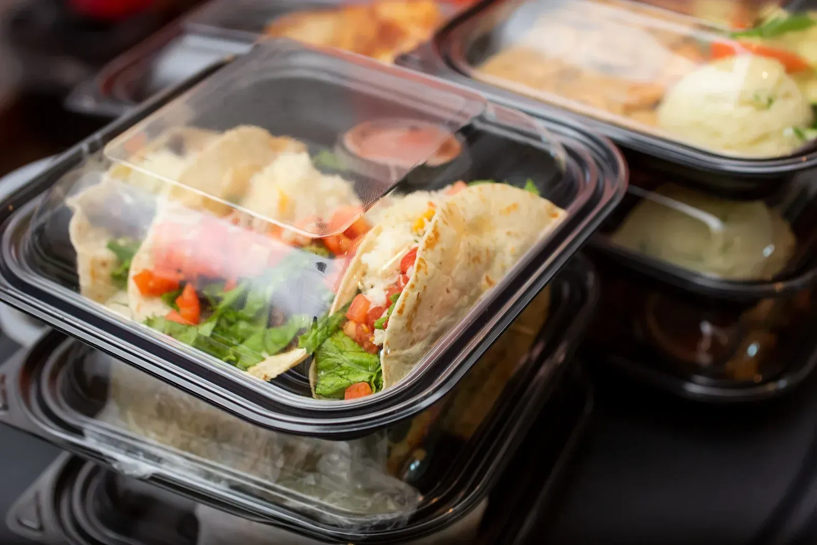 A stack of plastic containers filled with food on a table.