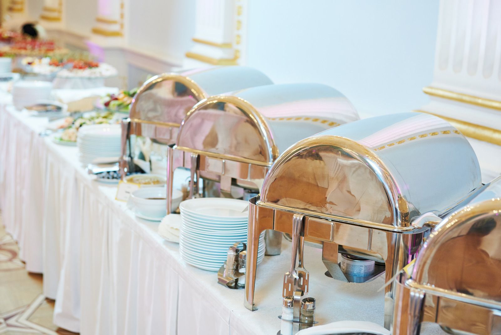 A buffet table with a variety of food and plates on it.
