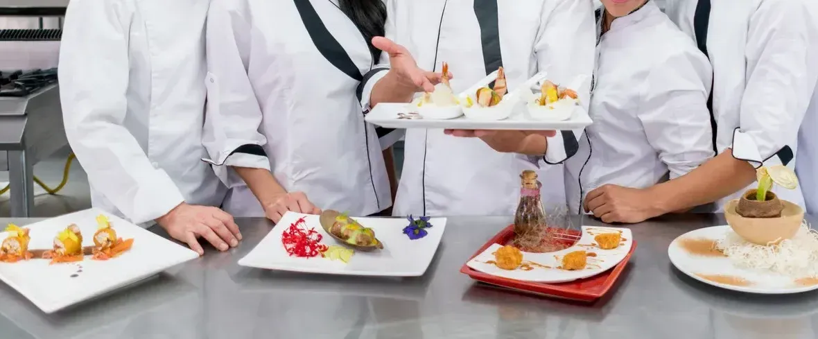 A group of chefs are standing around a table holding plates of food.