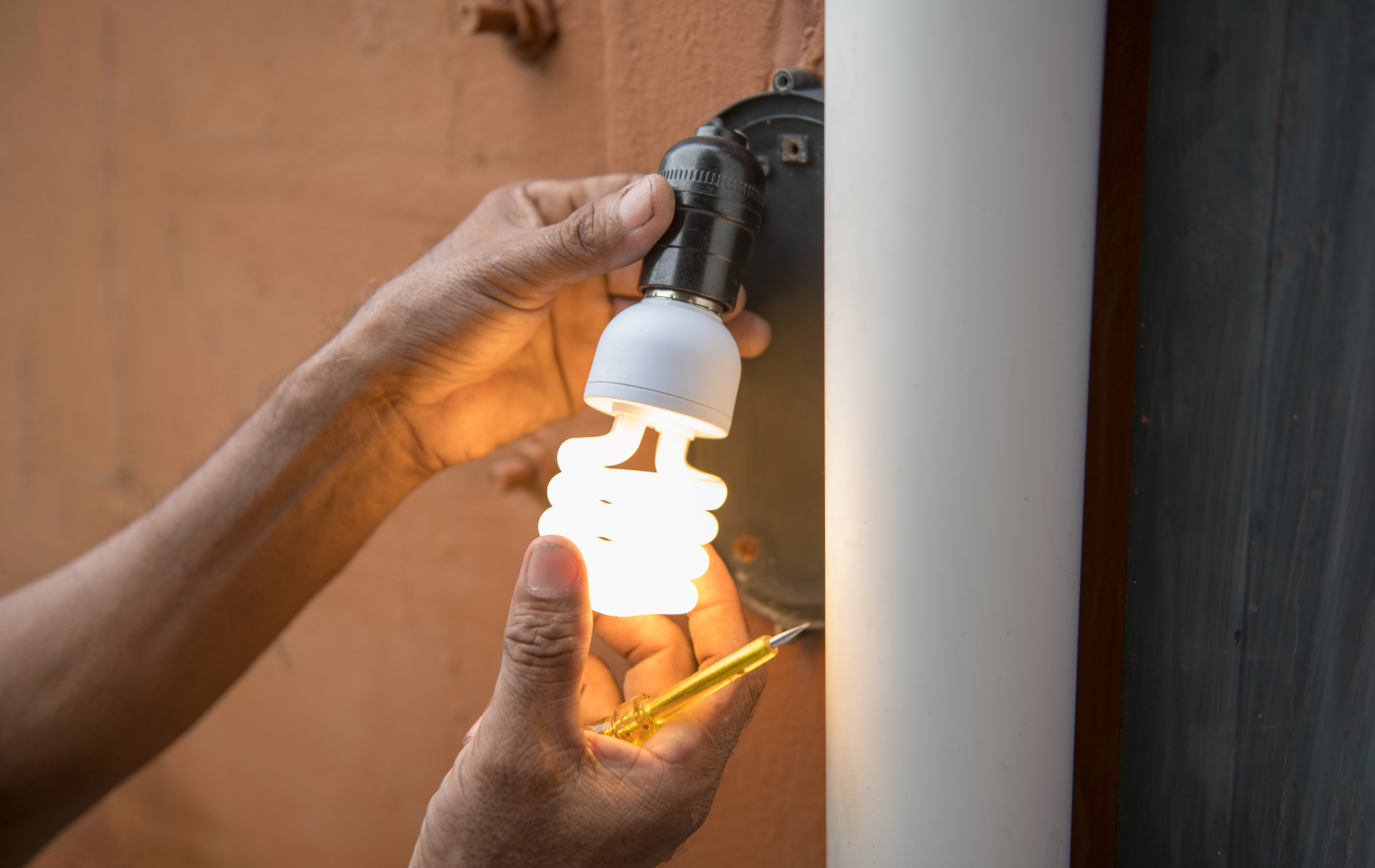 A person is changing a light bulb on a pole.